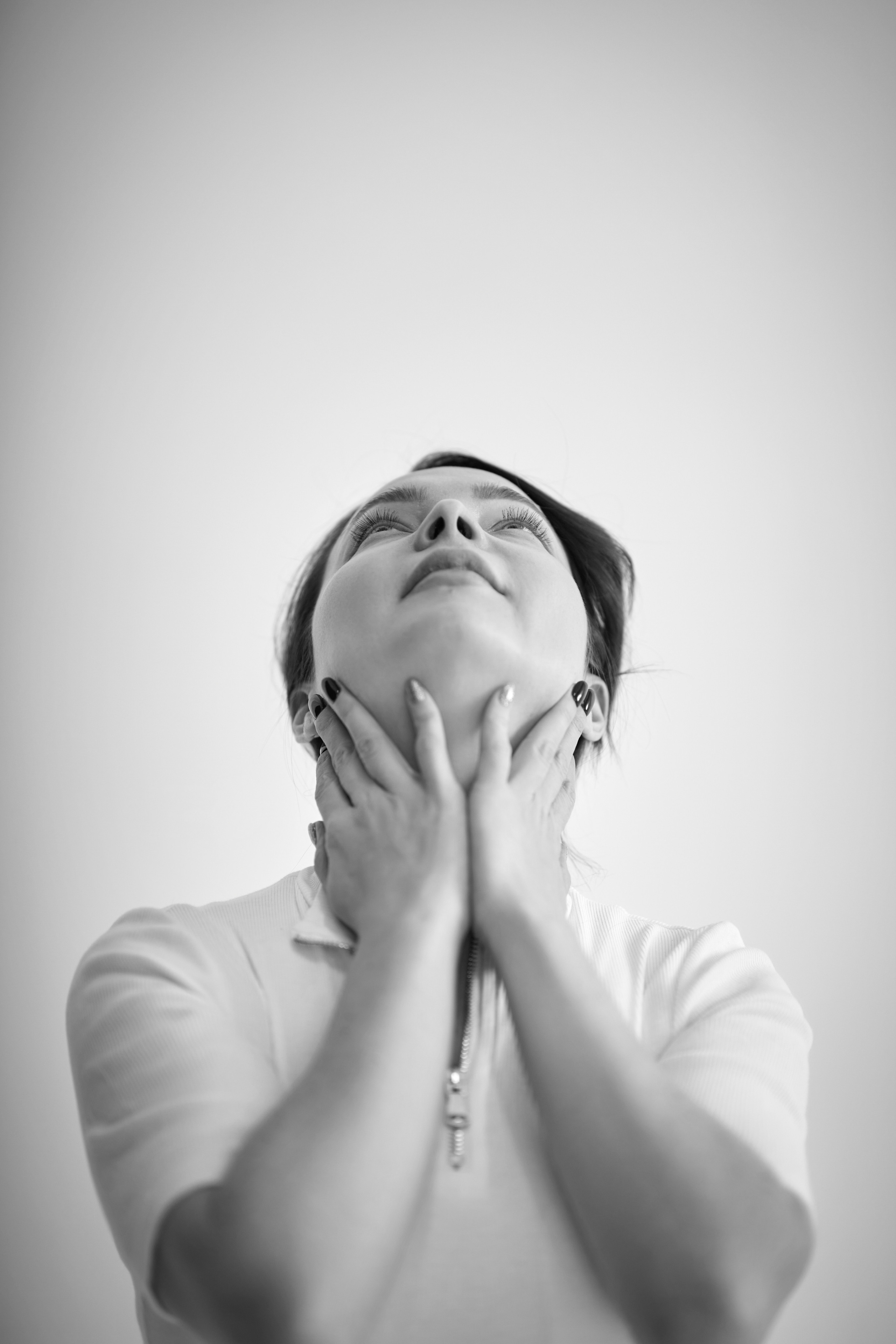 Темноволосая модель Татьяна сидит на стуле в светлом платье на светлом фоне.