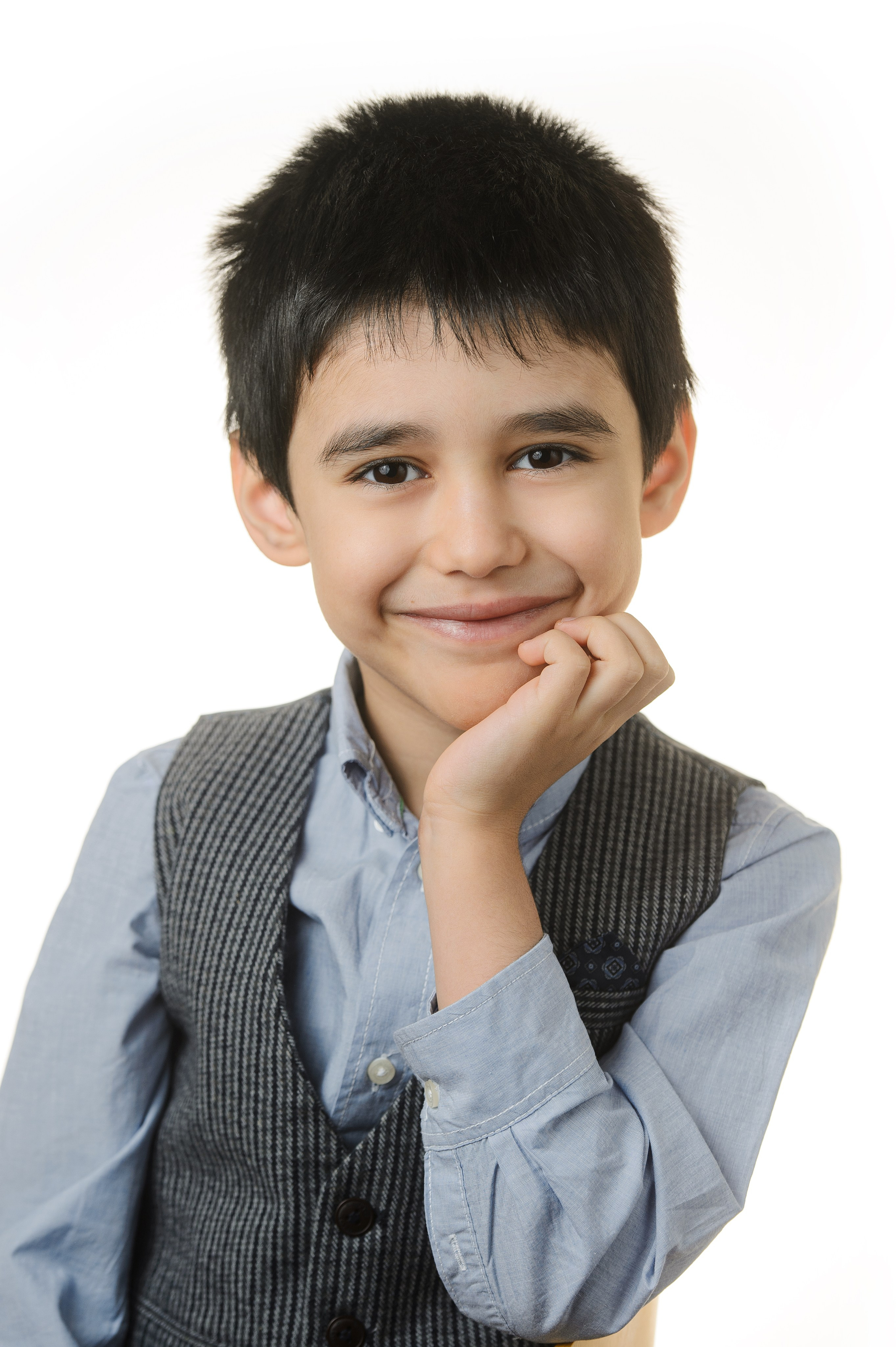 Мальчик в школьной жилетке опирается на руку в портрете на белом фоне.