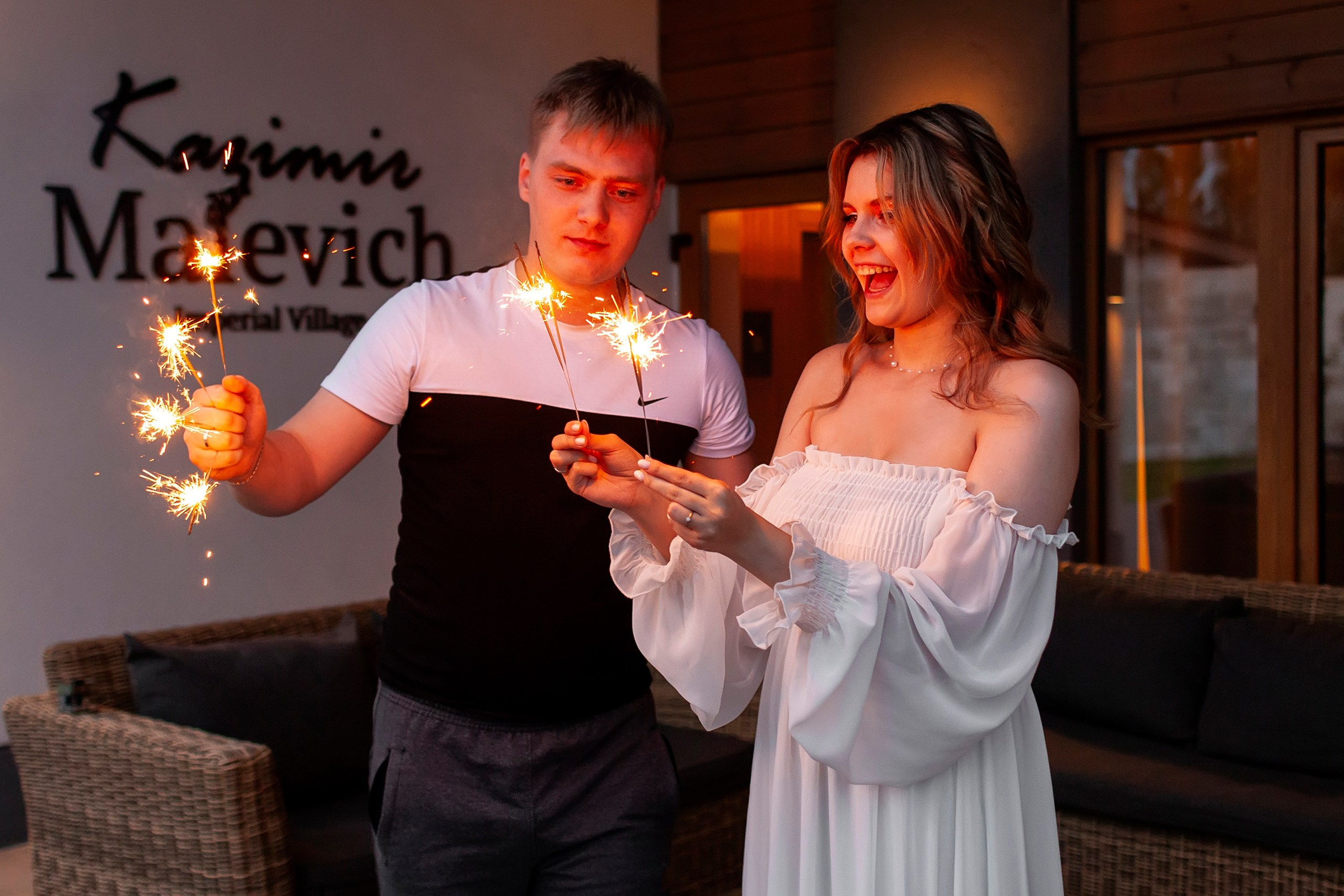 Пара зажигает бенгальские огни около дома