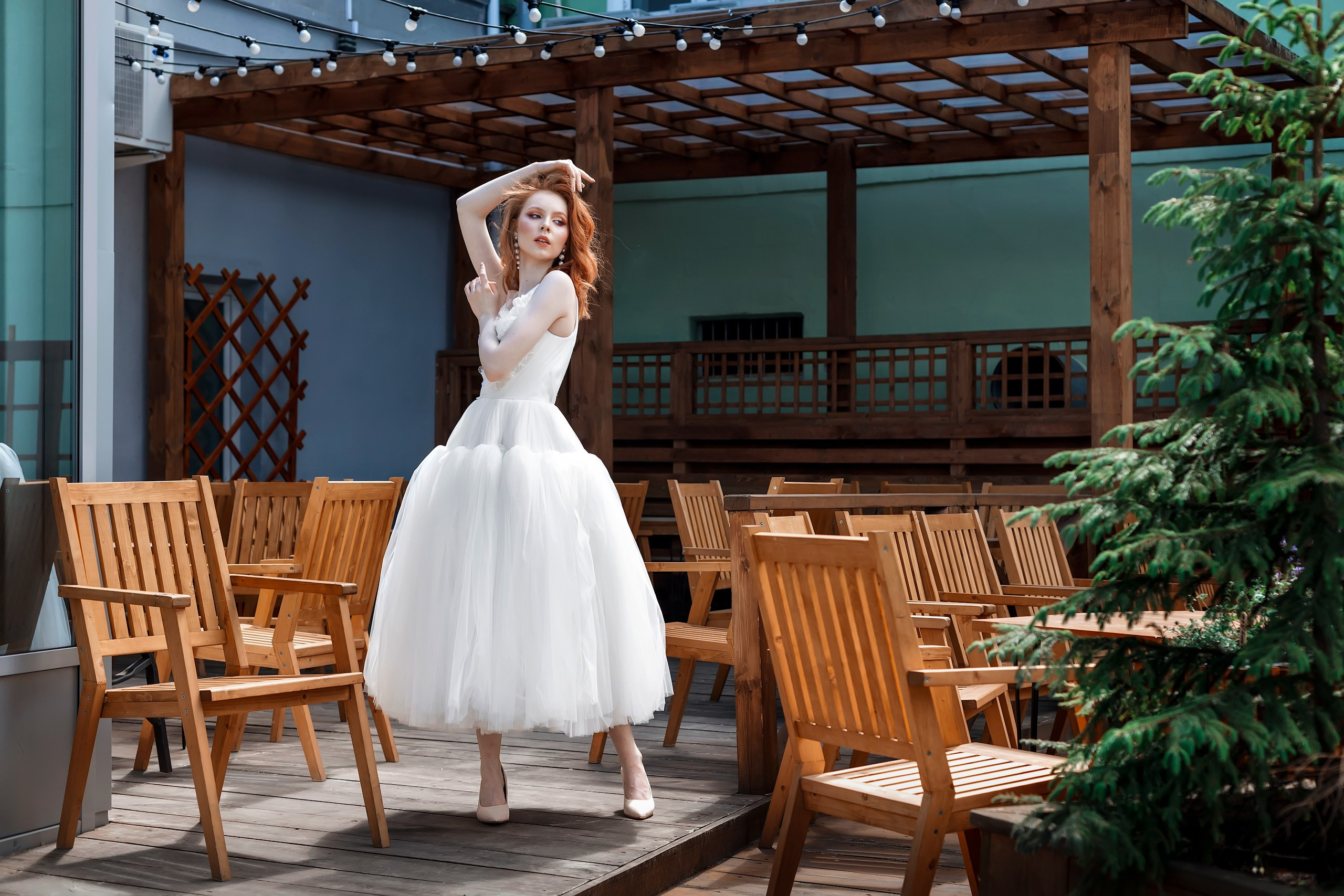 Девушка с рыжими волосами стоит посреди пустого летнего кафе - прогулочная фотосессия Ульяновск