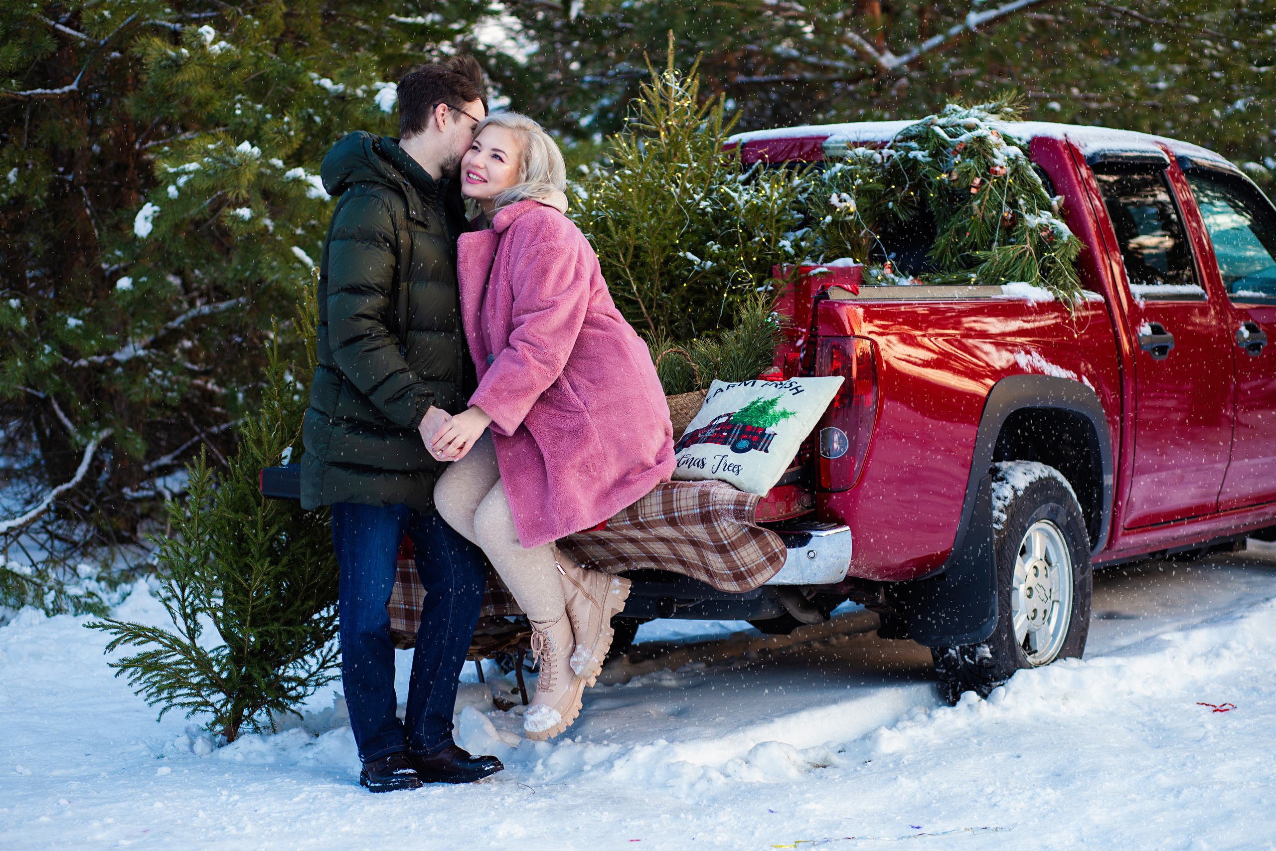 девушка  в розовой  шубе   и молодой человек  целуются. на  фоне красный  пикап.