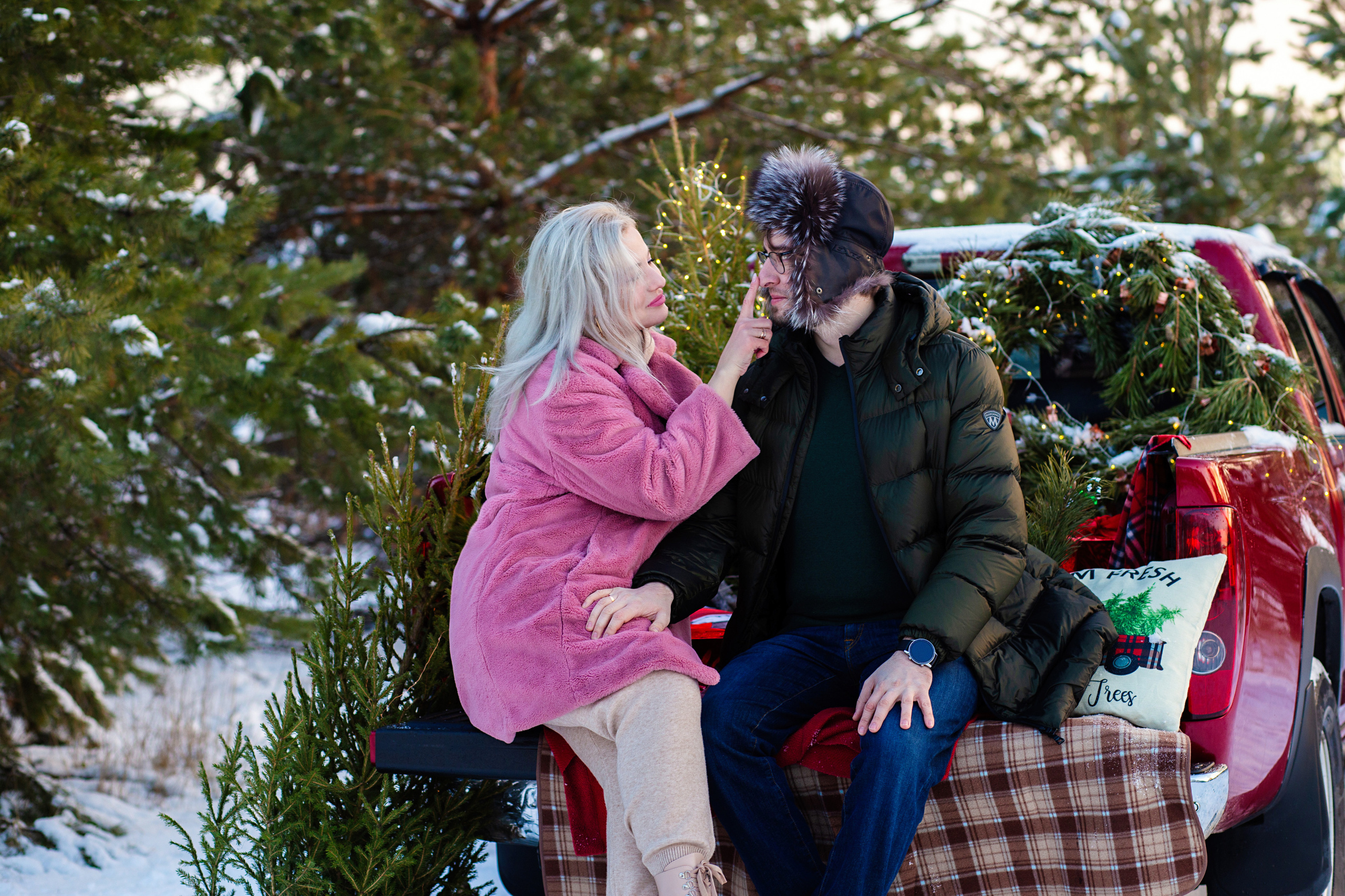 девушка  в розовой  шубе   и молодой человек  целуются. на  фоне красный  пикап.