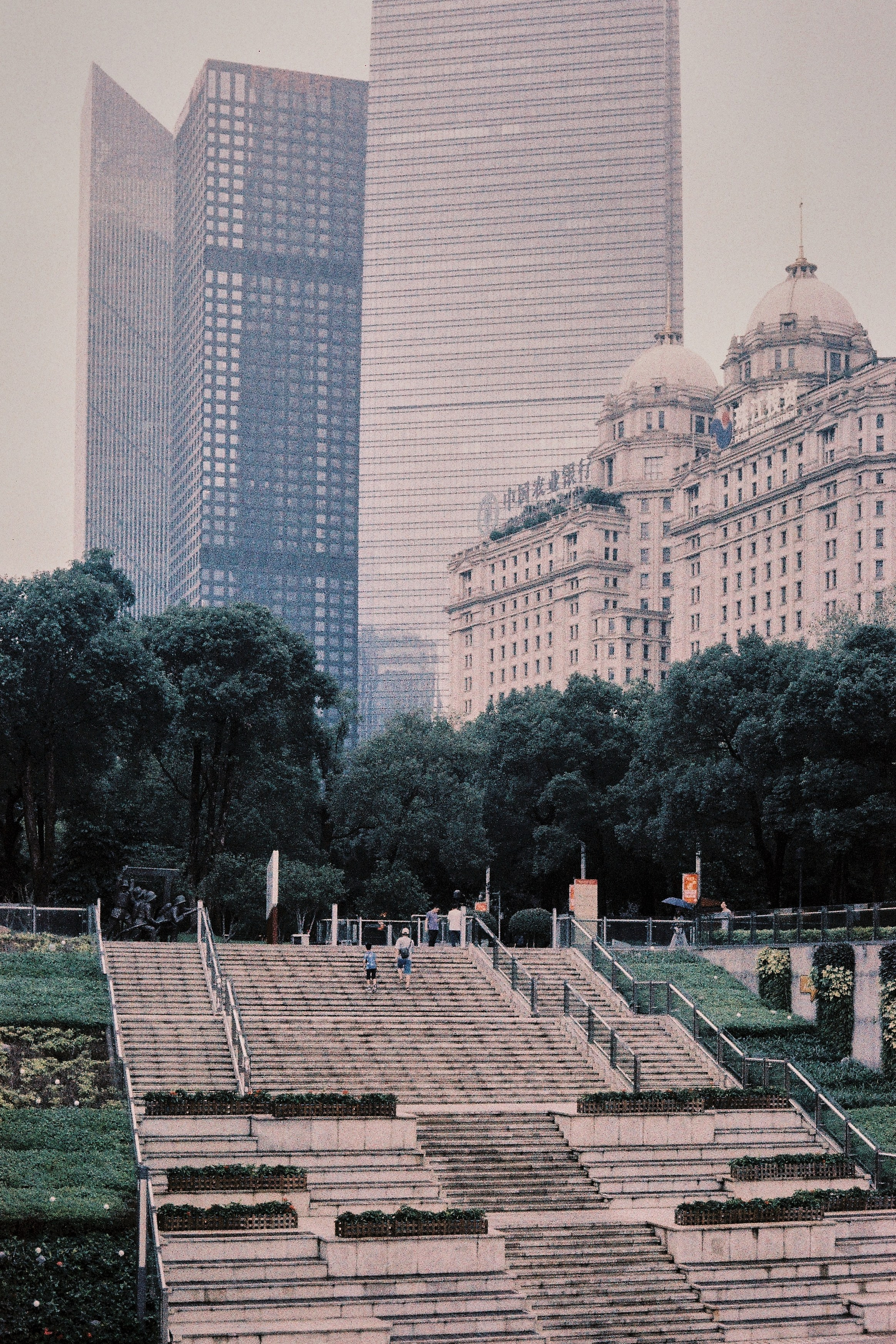 Две мелкие фигуры людей поднимаются по масштабной лестнице в центральном районе Гуанчжоу, Китай
