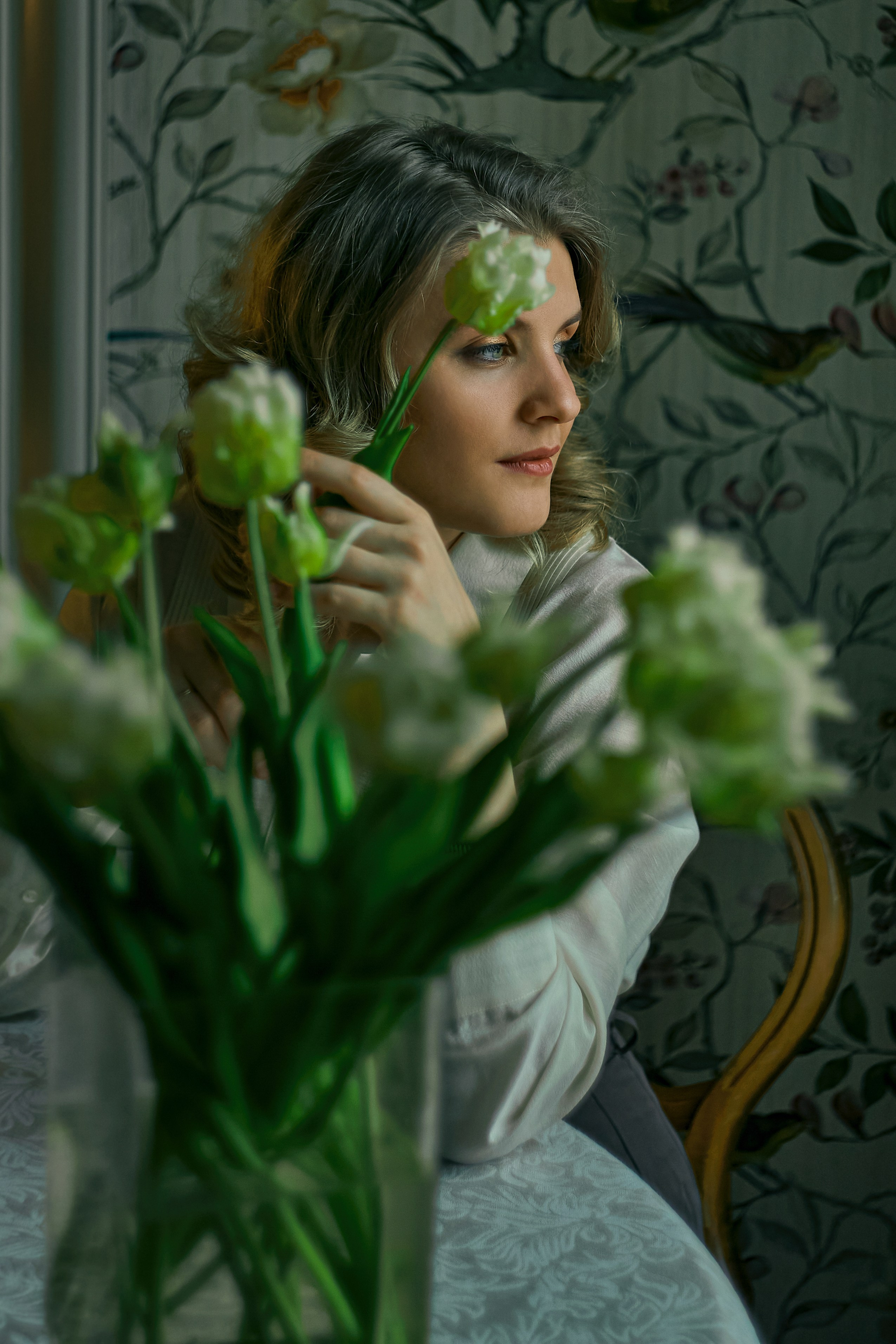 Блондинка в ретро стиле лежит на диване с белыми тюльпанами в руке