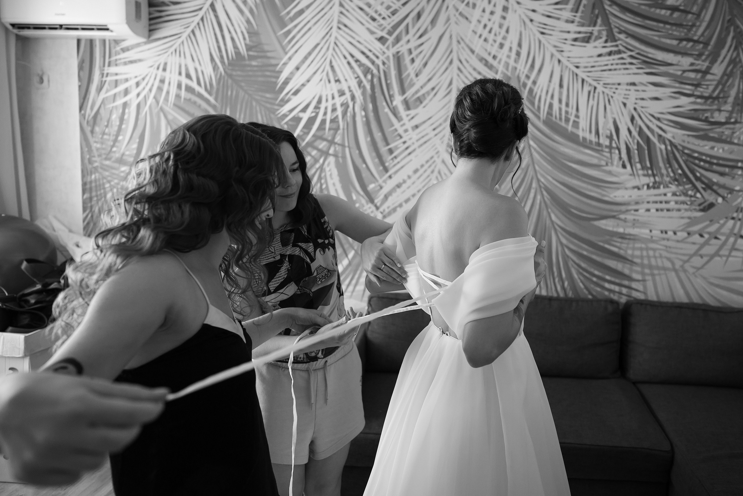 Подруги помогают невесте надеть свадебное платье в Краснодаре.