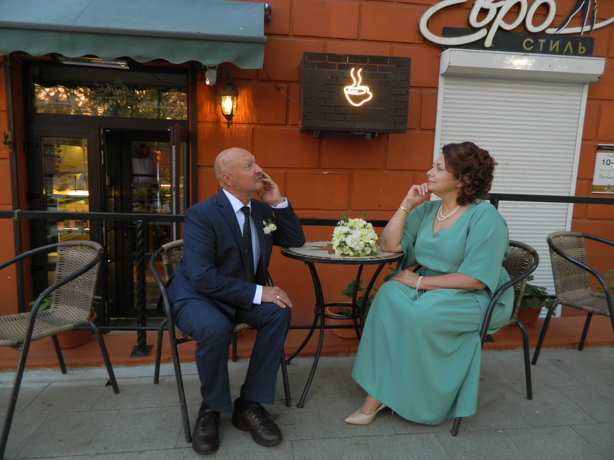 муж и жена сидят в летнем кафе и любуются друг другом