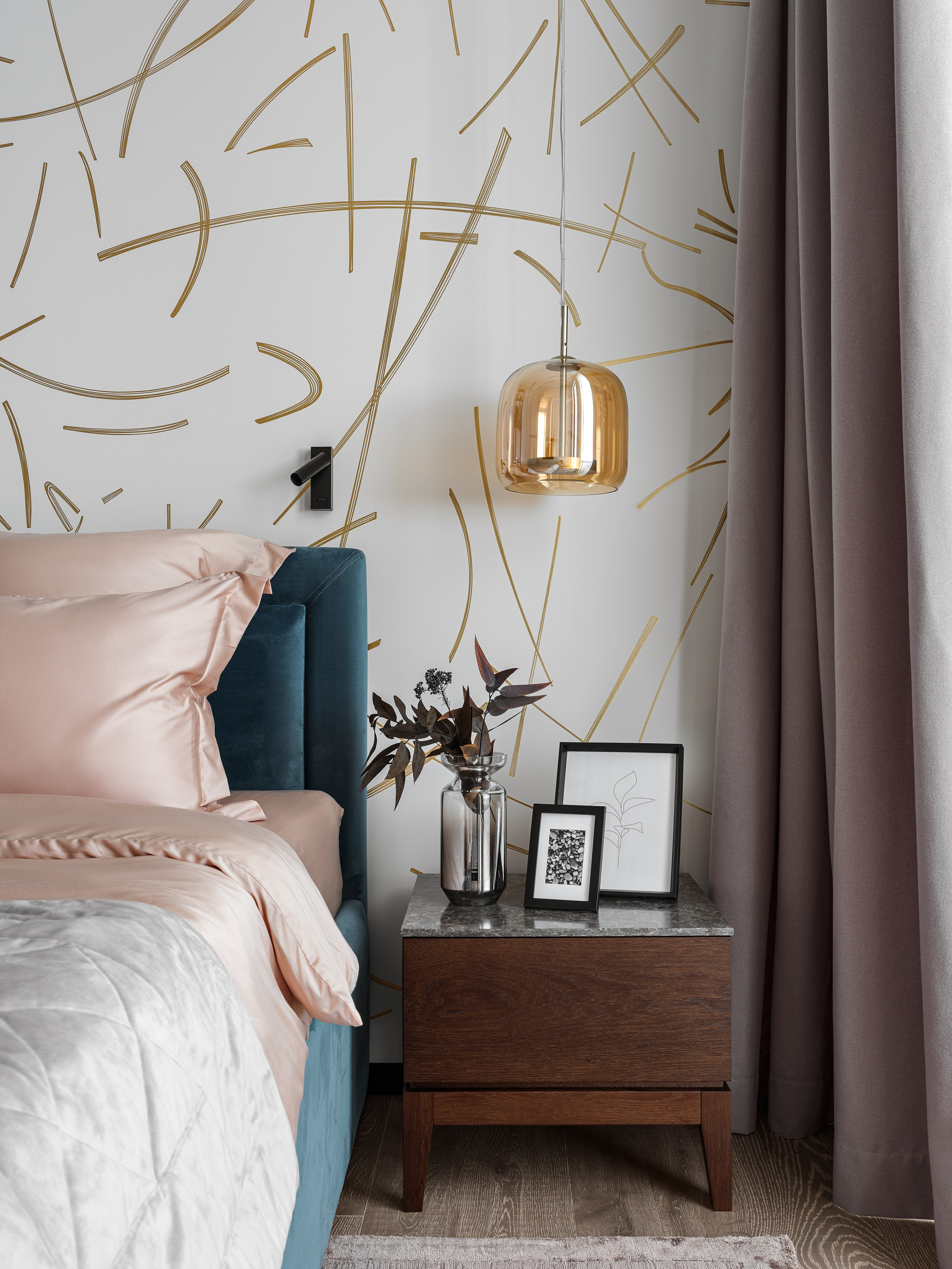 Современная спальня с мягким изголовьем из бархатной ткани, прикроватной тумбой из массива дерева, стеклянной вазой и подвесным светильником в золотом оттенке. Интерьер от дизайнеров Рената Байчукова и Алеси Кириенко, стилиста Екатерины Ракитиной, фотографа Сергея Денисенко.