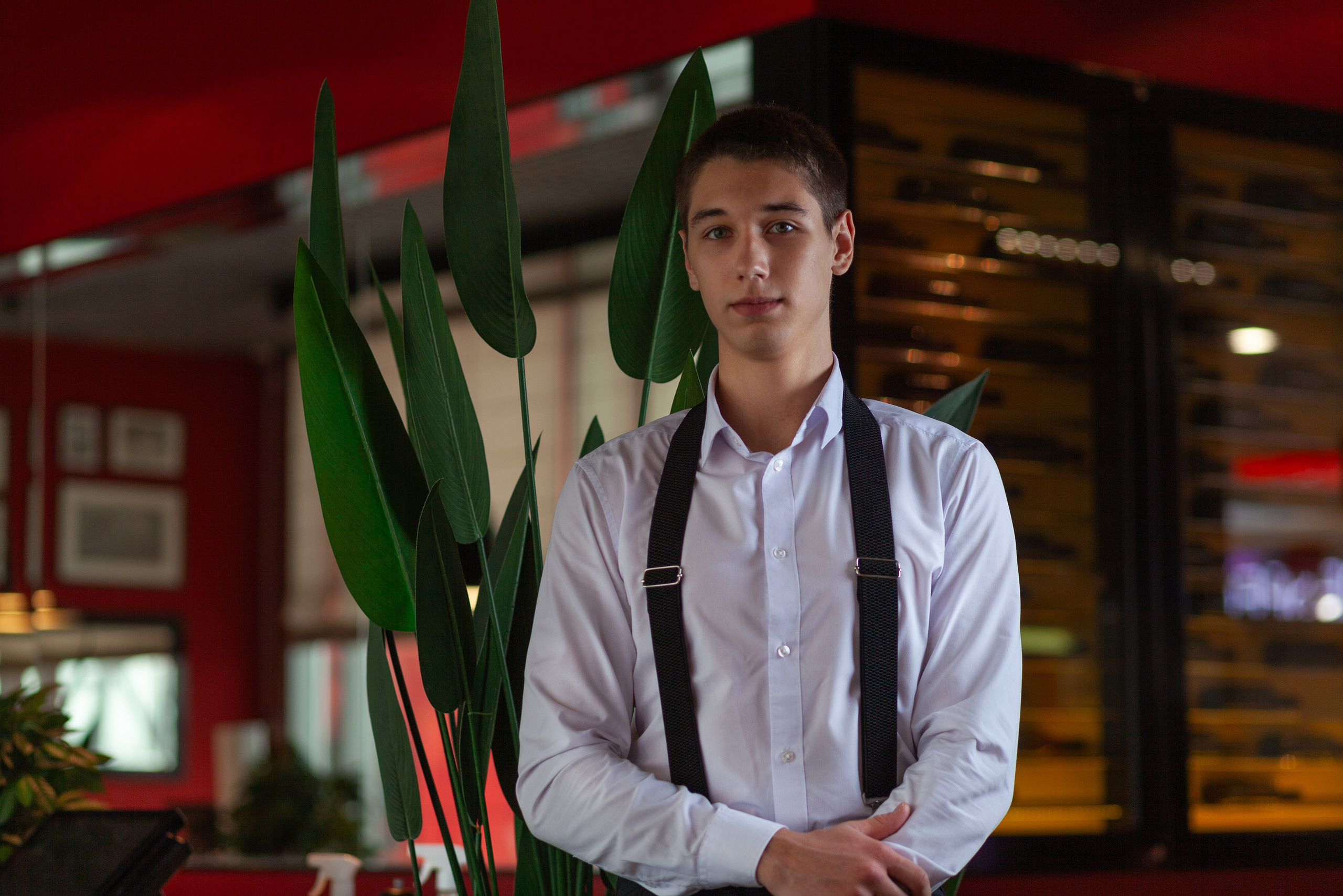 Мужчина в подтяжках стоит на фоне интерьера кафе