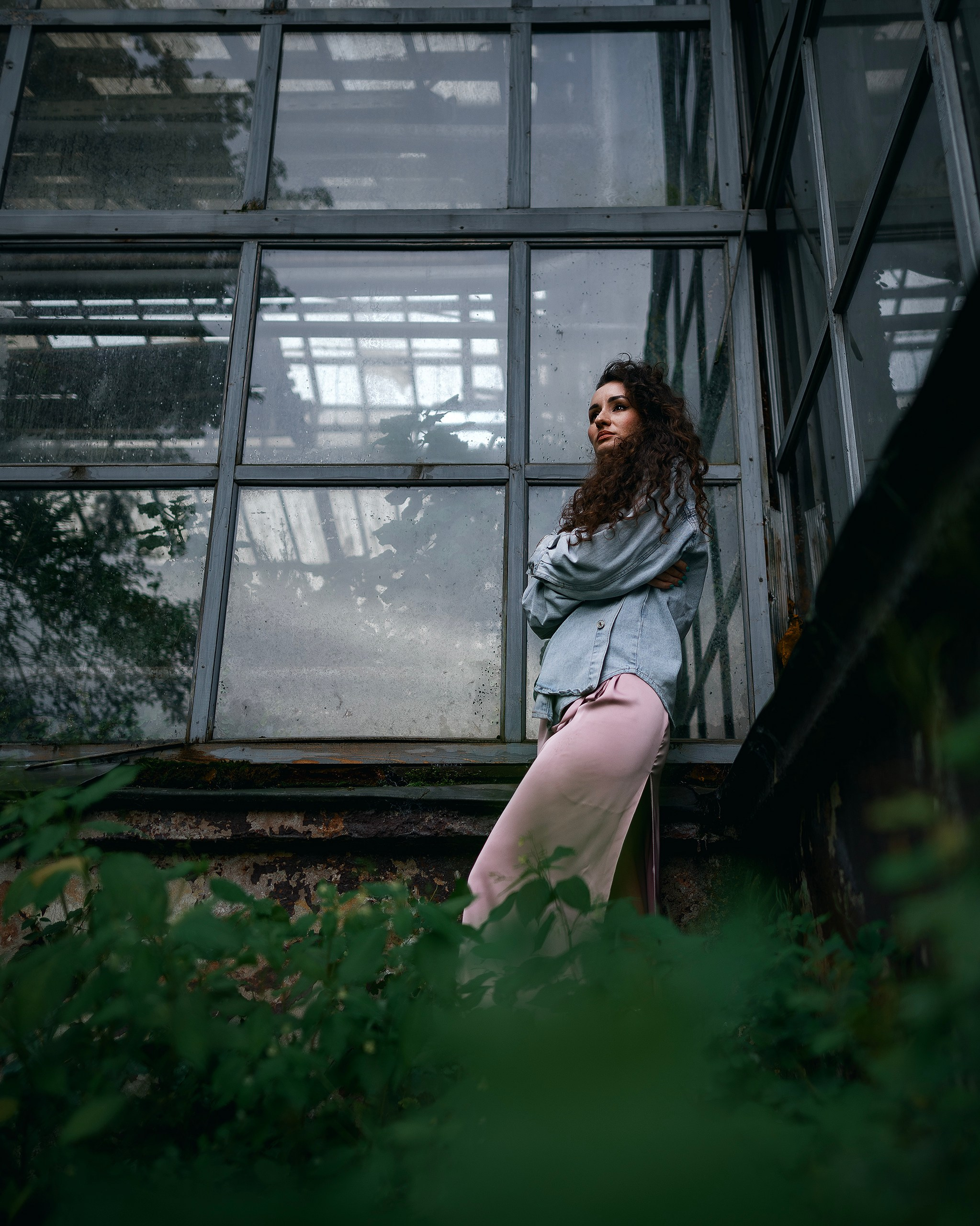 Девушка в платье стоит на фоне зелени