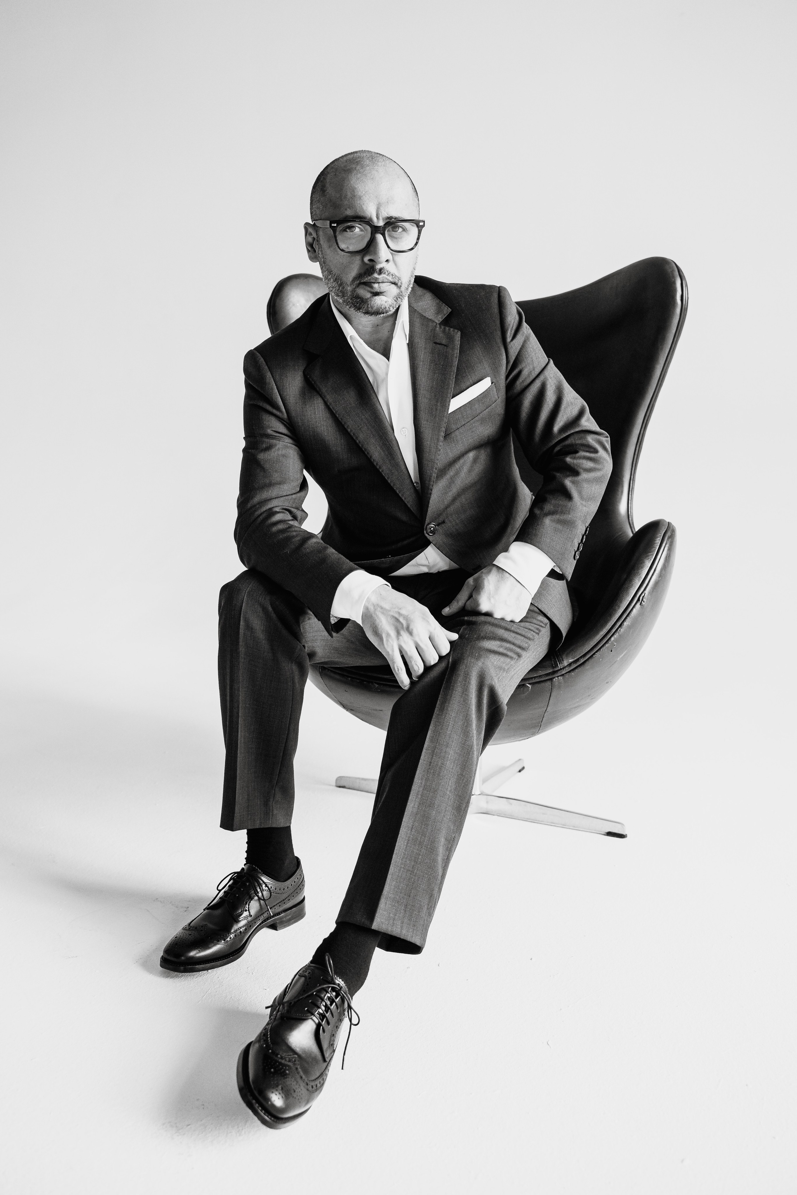 Мужчина в деловом костюме, сидящий у нотной тетради — креативная бизнес-съёмка.