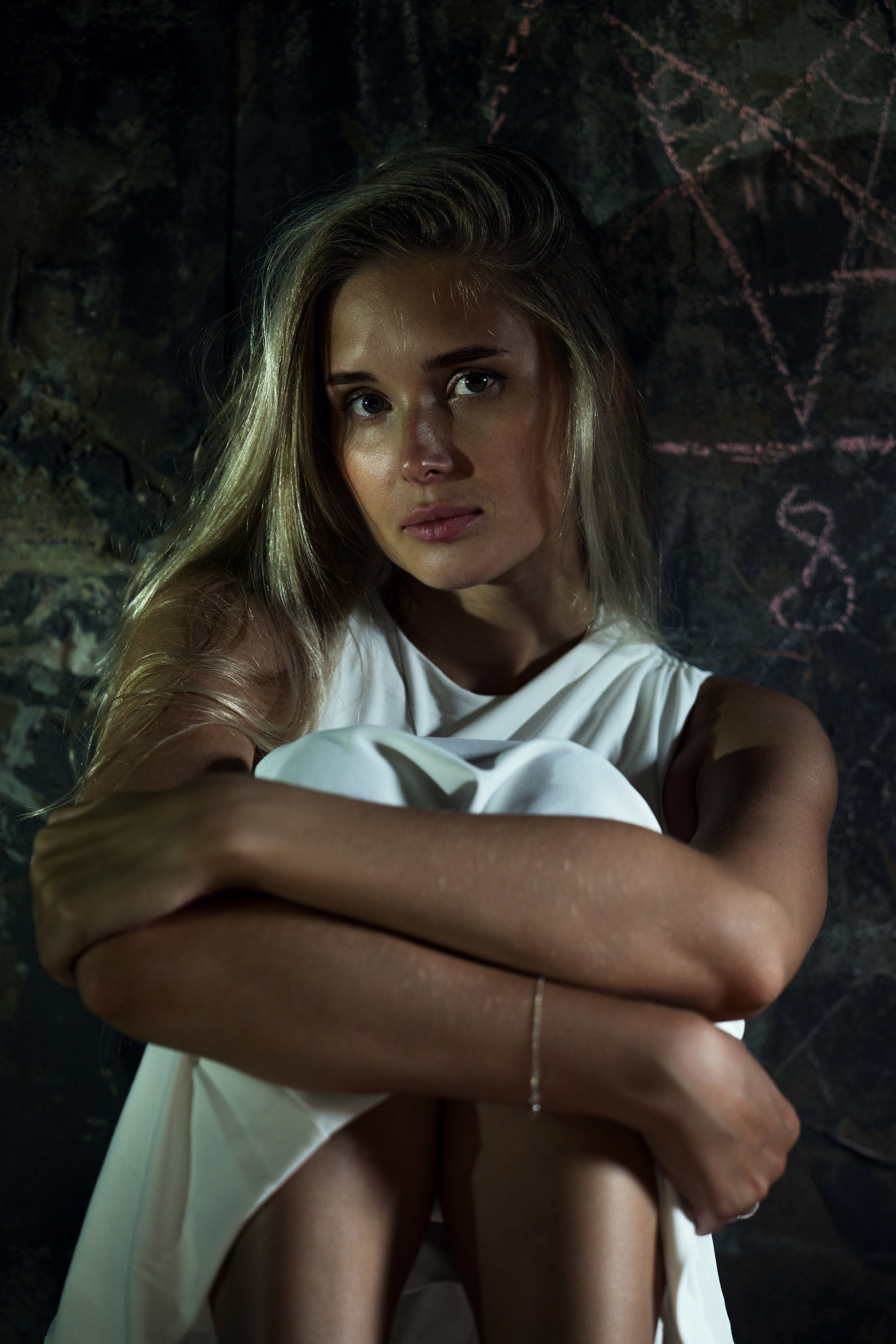 красивая девушка с задумчивым взглядом в платье в темной локации 