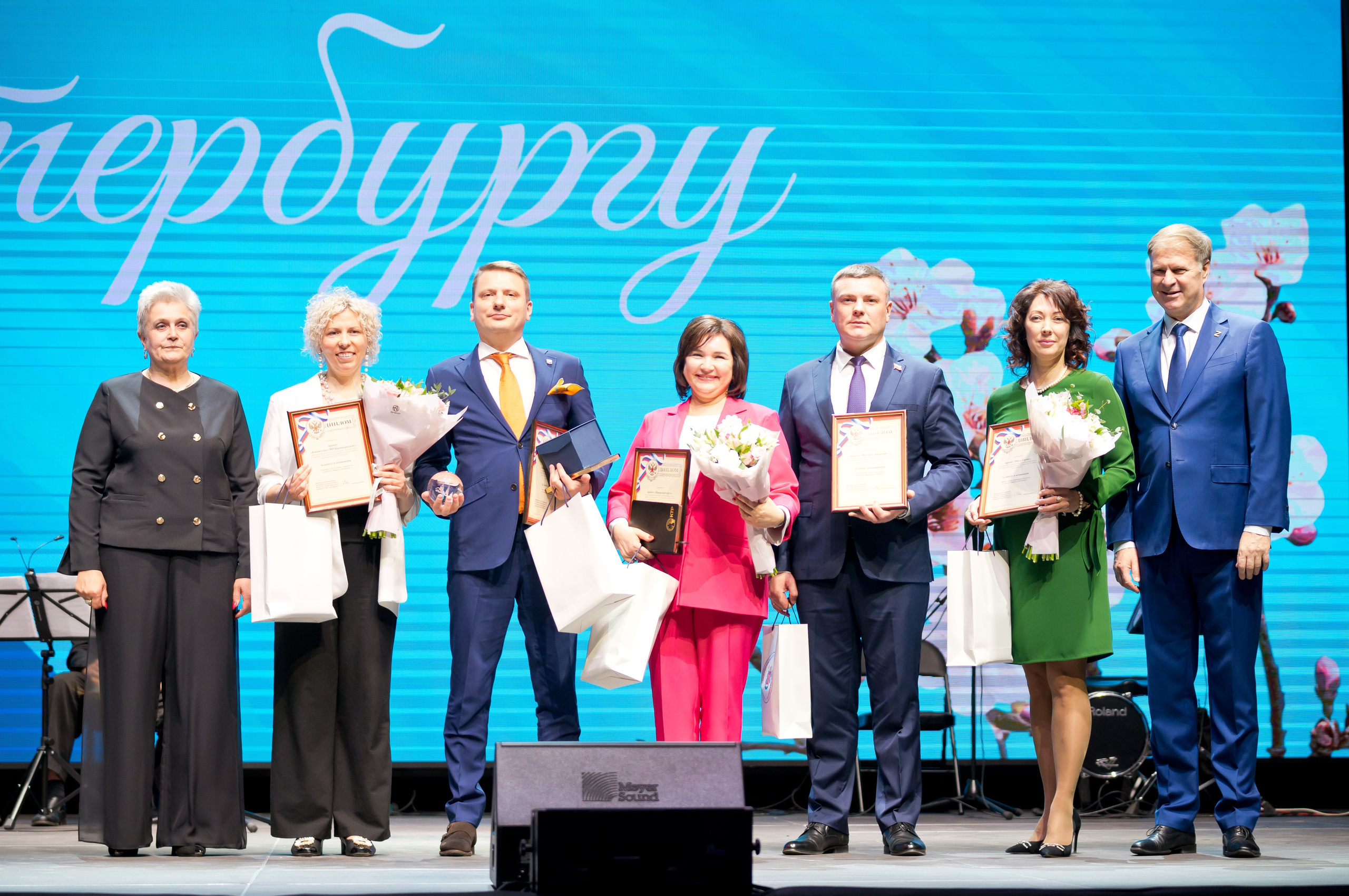 Групповое фото победителей и организаторов Дня местного самоуправления Санкт-Петербурга на сцене с наградами и цветами | Фото: Евгений Мальцев.