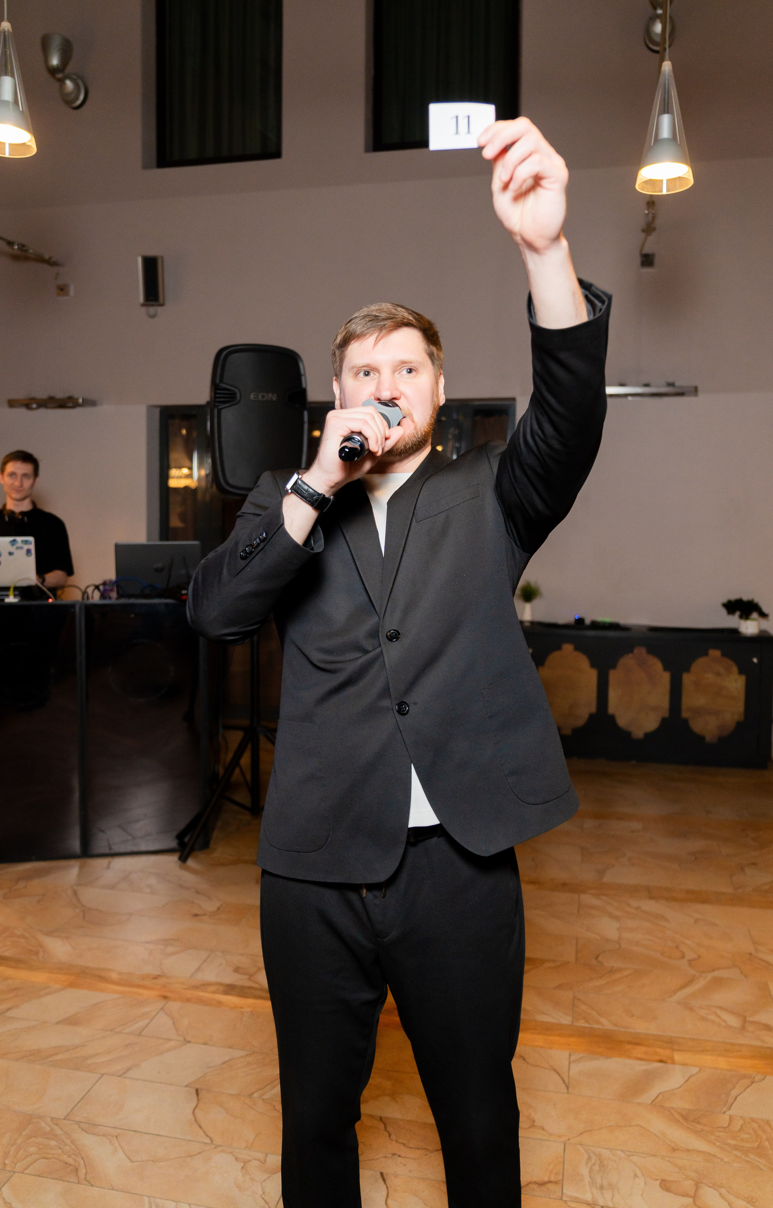 Ведущий поднимает карточку с номером 11 и объявляет победителя розыгрыша на мероприятии Radisson Sonya. Фото Евгения Мальцева (evrednix.ru).