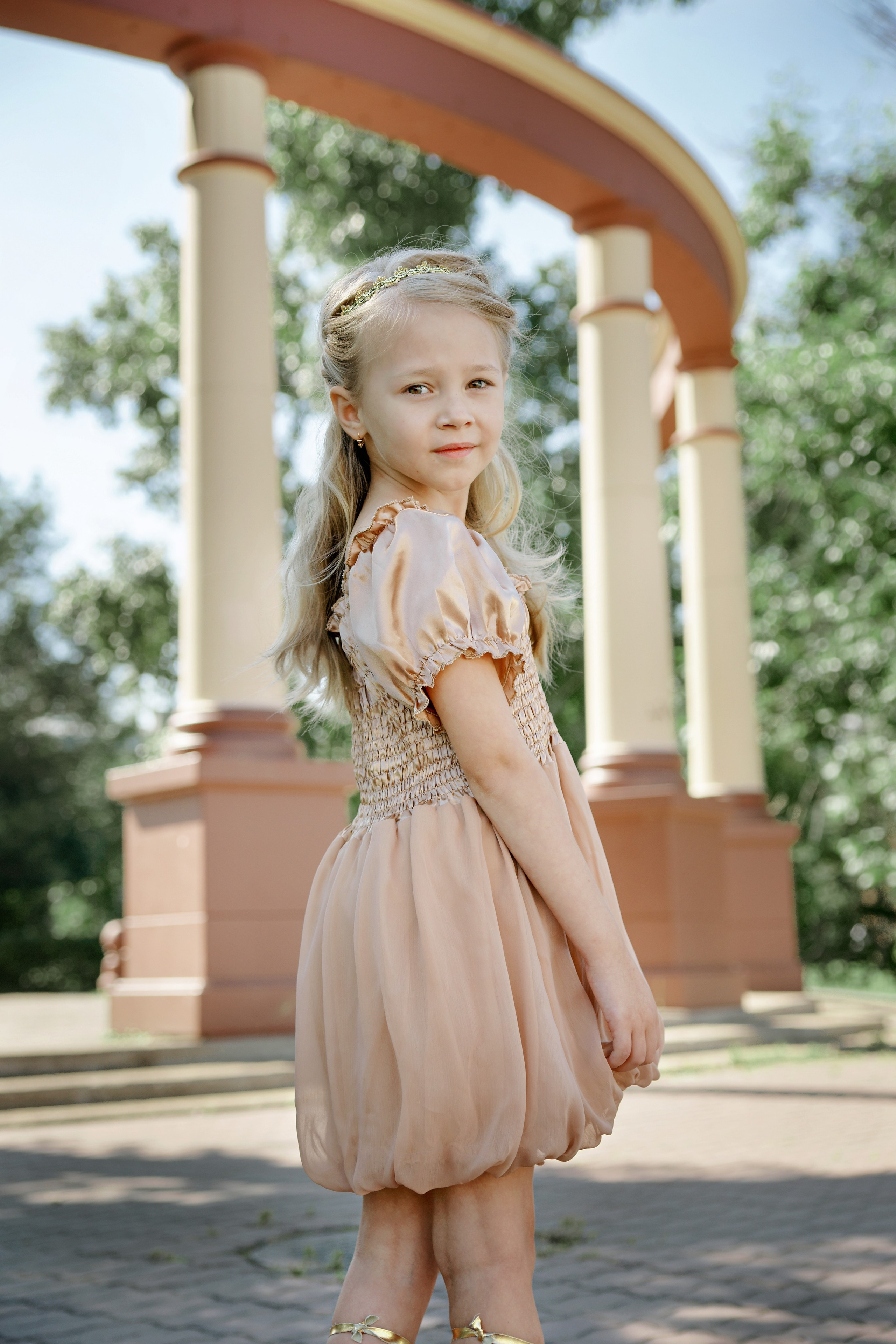 Детская фотосессия летом - девочка стоя у арки в греческом стиле
