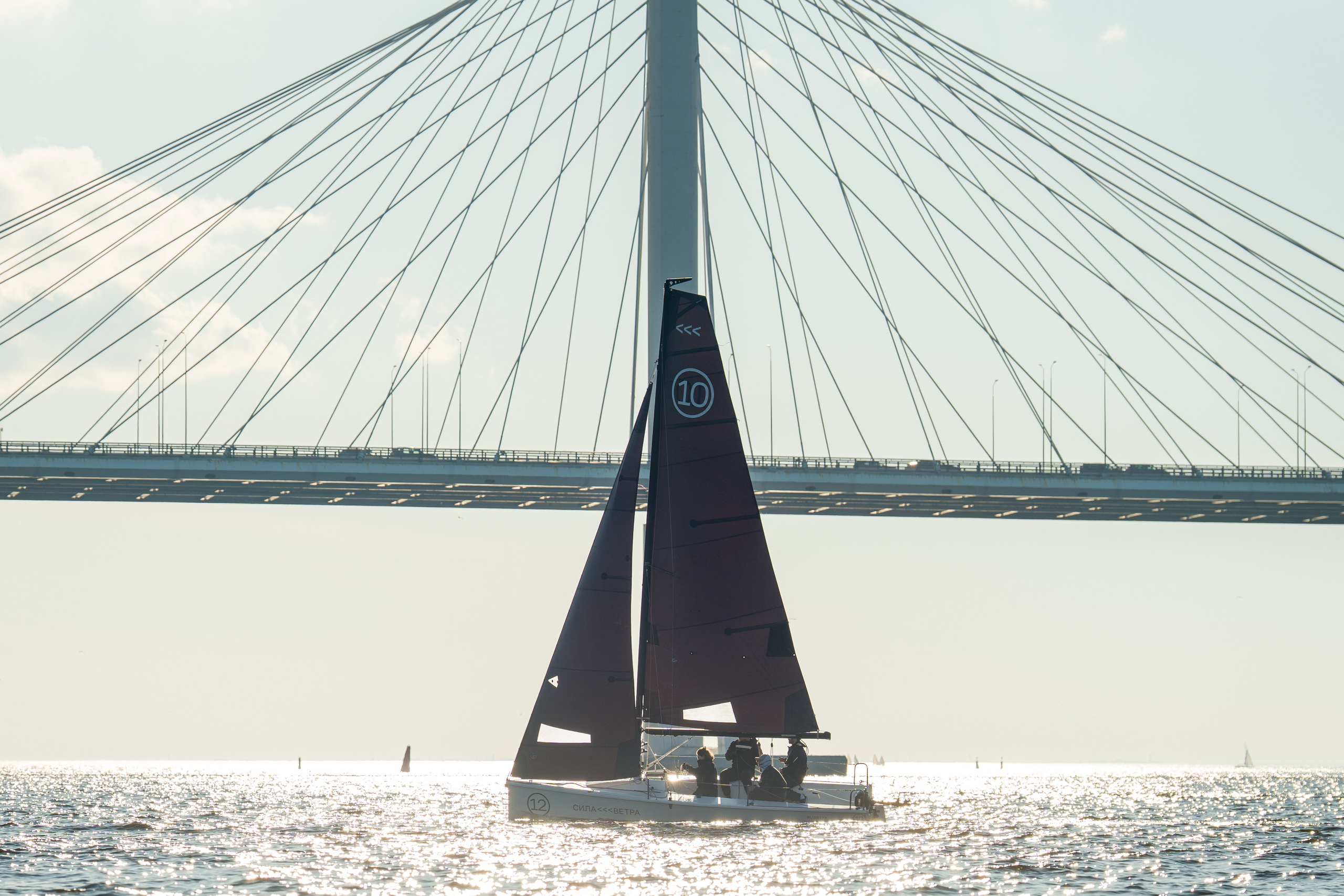 SV20 sails under a gennaker in sun, bridge in the background