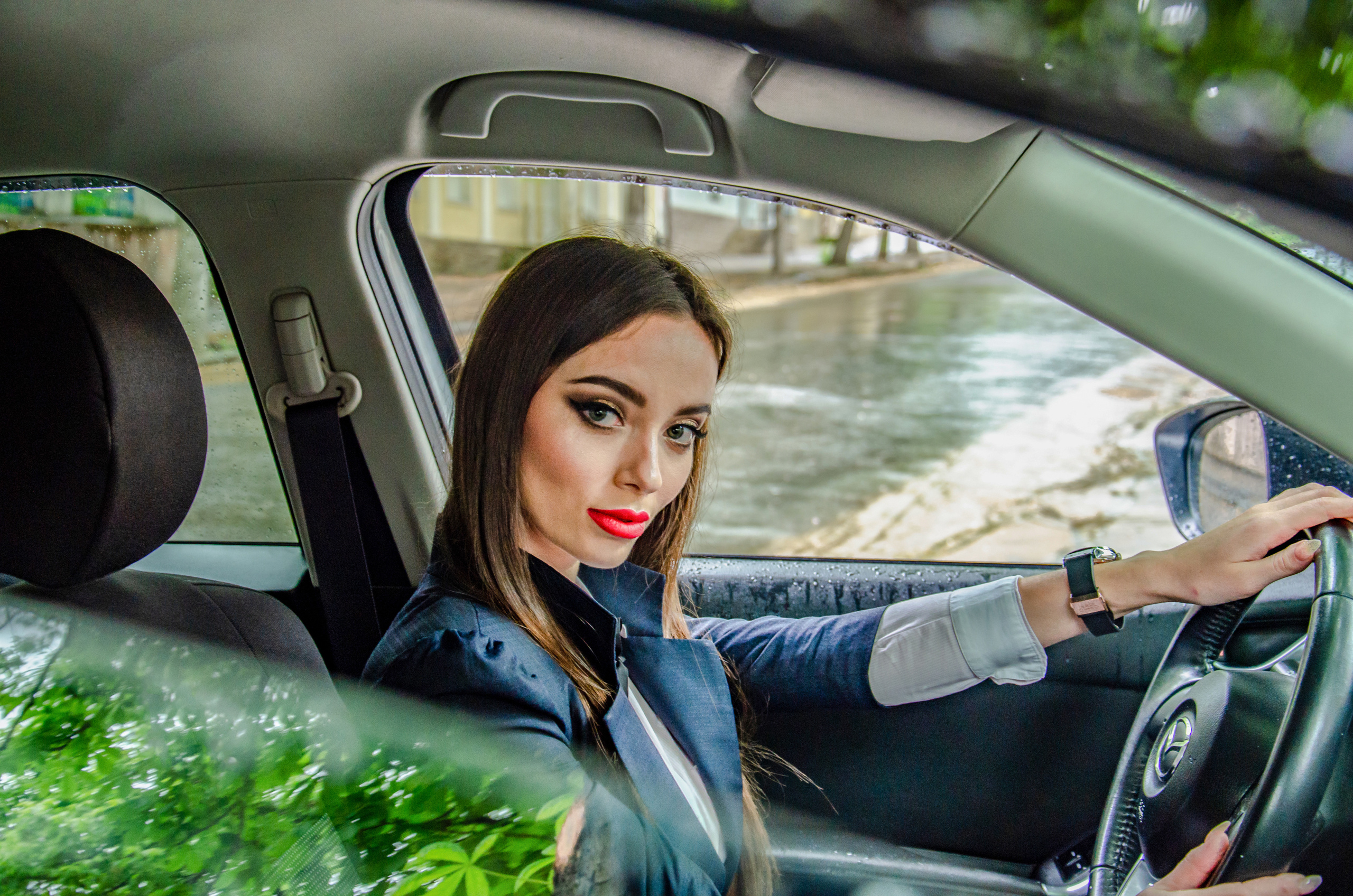 Девушка за рулем машины смотрит в открытое окно