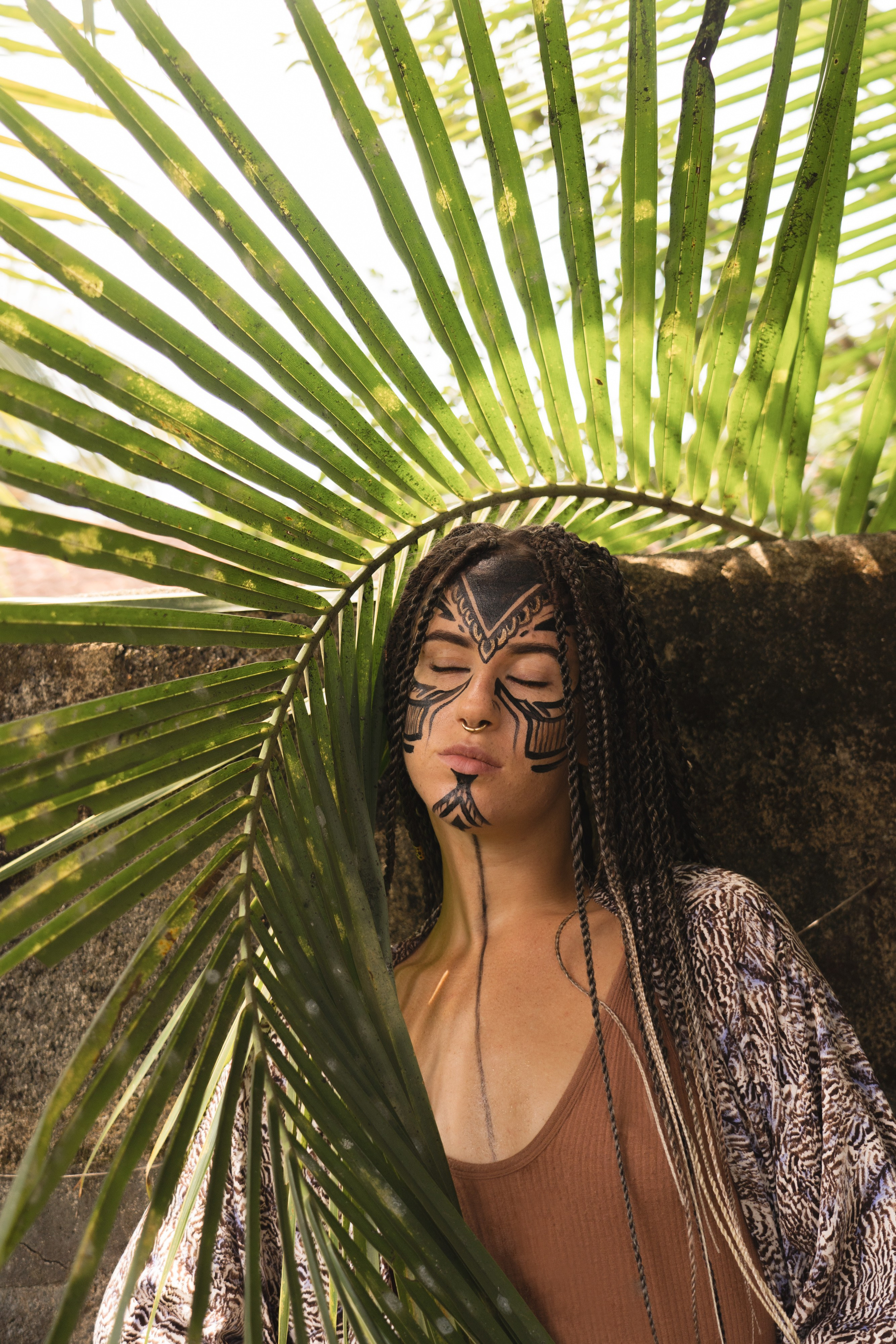 Girl with face paint as an Amazon next to a palm leaf