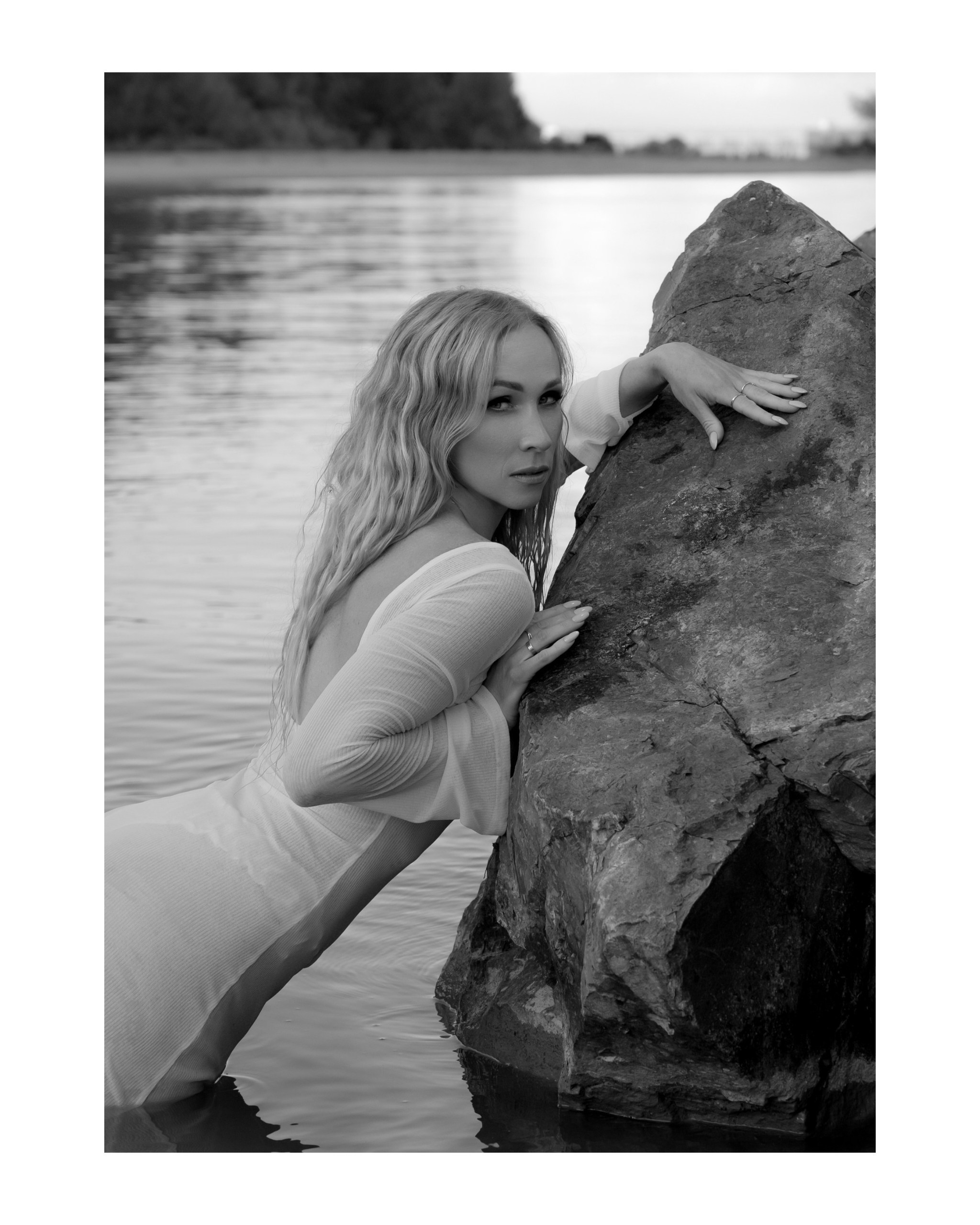 чб фото девушки в пляжном платье-паутинке в воде у камня