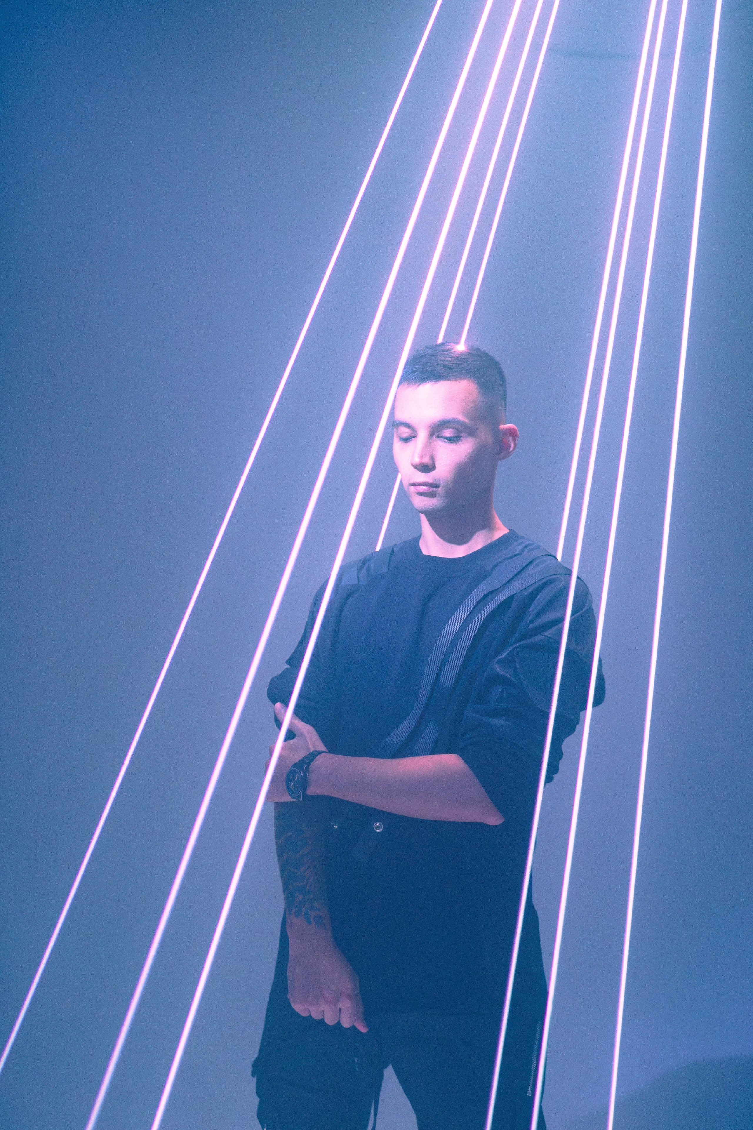 Мужчина позирует перед вертикальными лазерными лучами