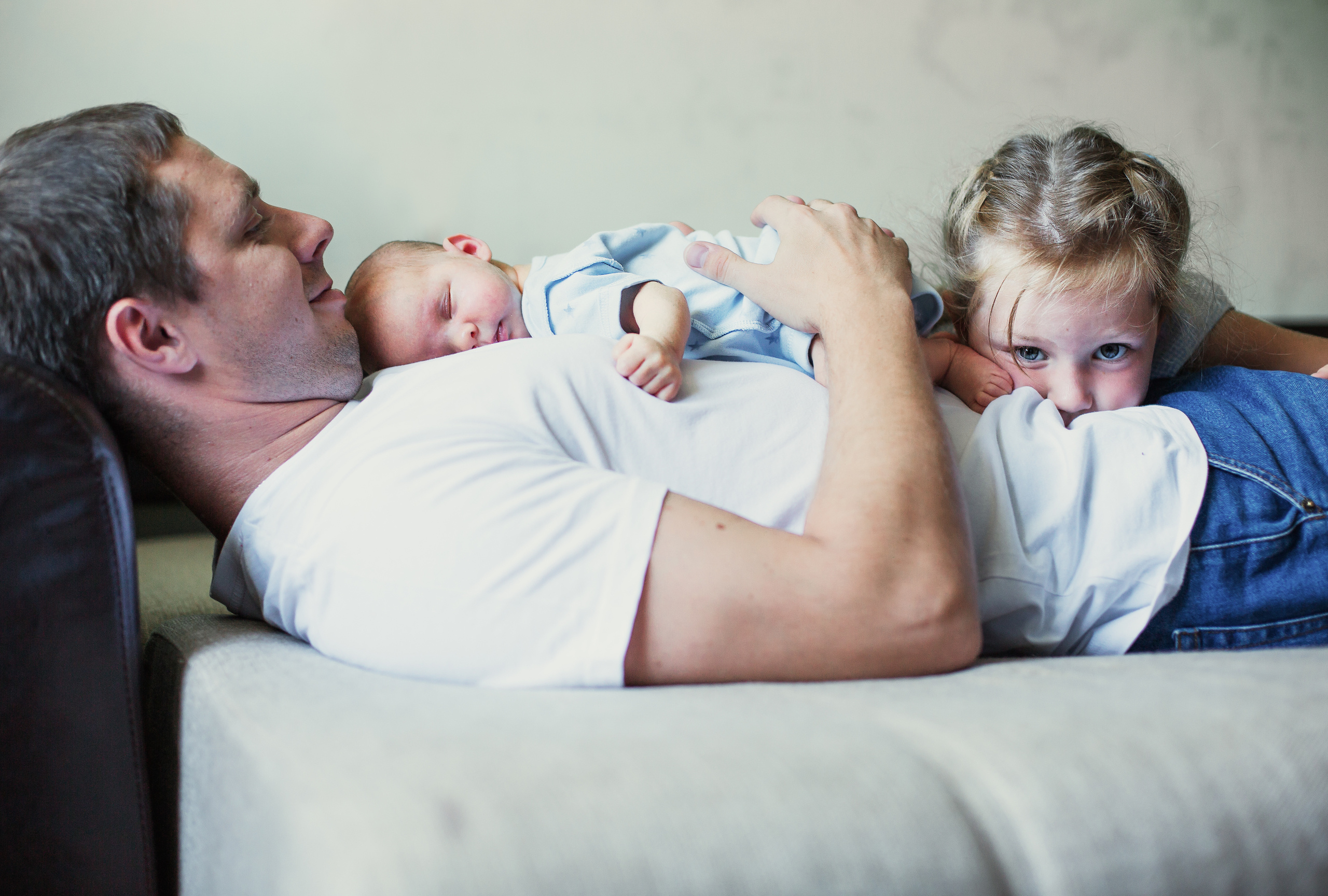 Новорожденный спит у папы на груди в компании со старшей сестрой.