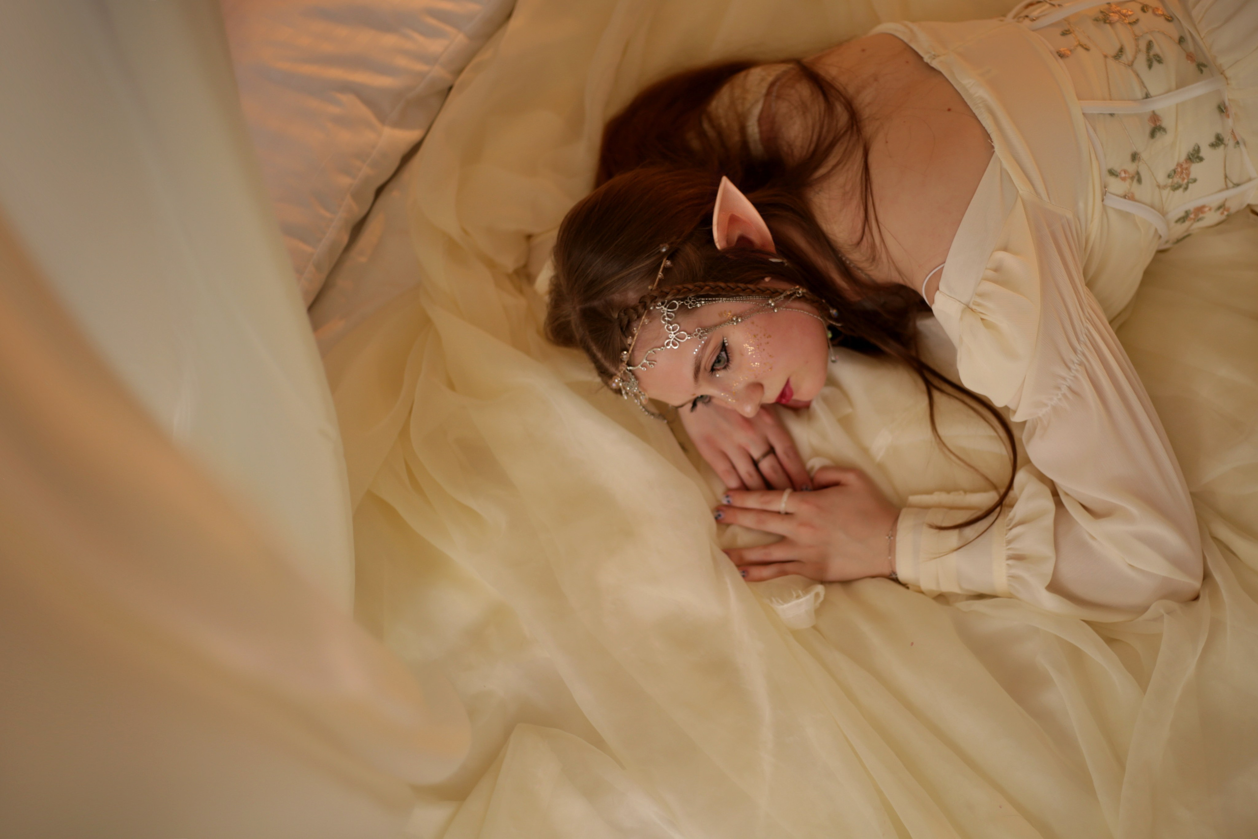 Эльфийская фотосессия в Перми: девушка в белом платье спит на кровати под балдахином, лицо украшено блестками