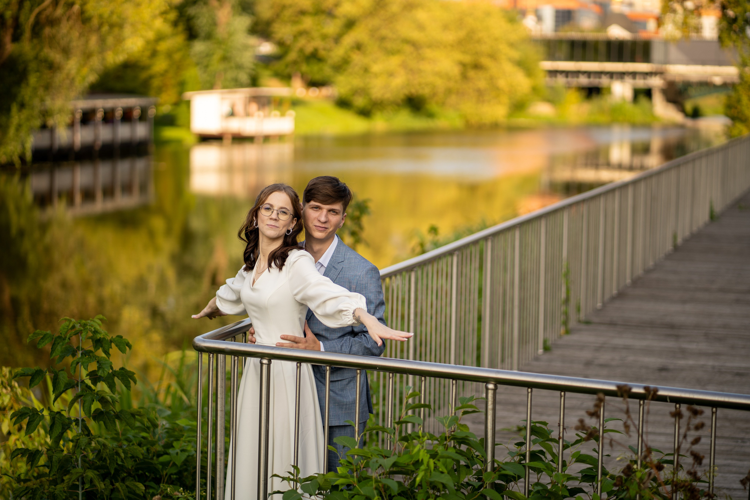 Молодожены стоят на мосту у реки