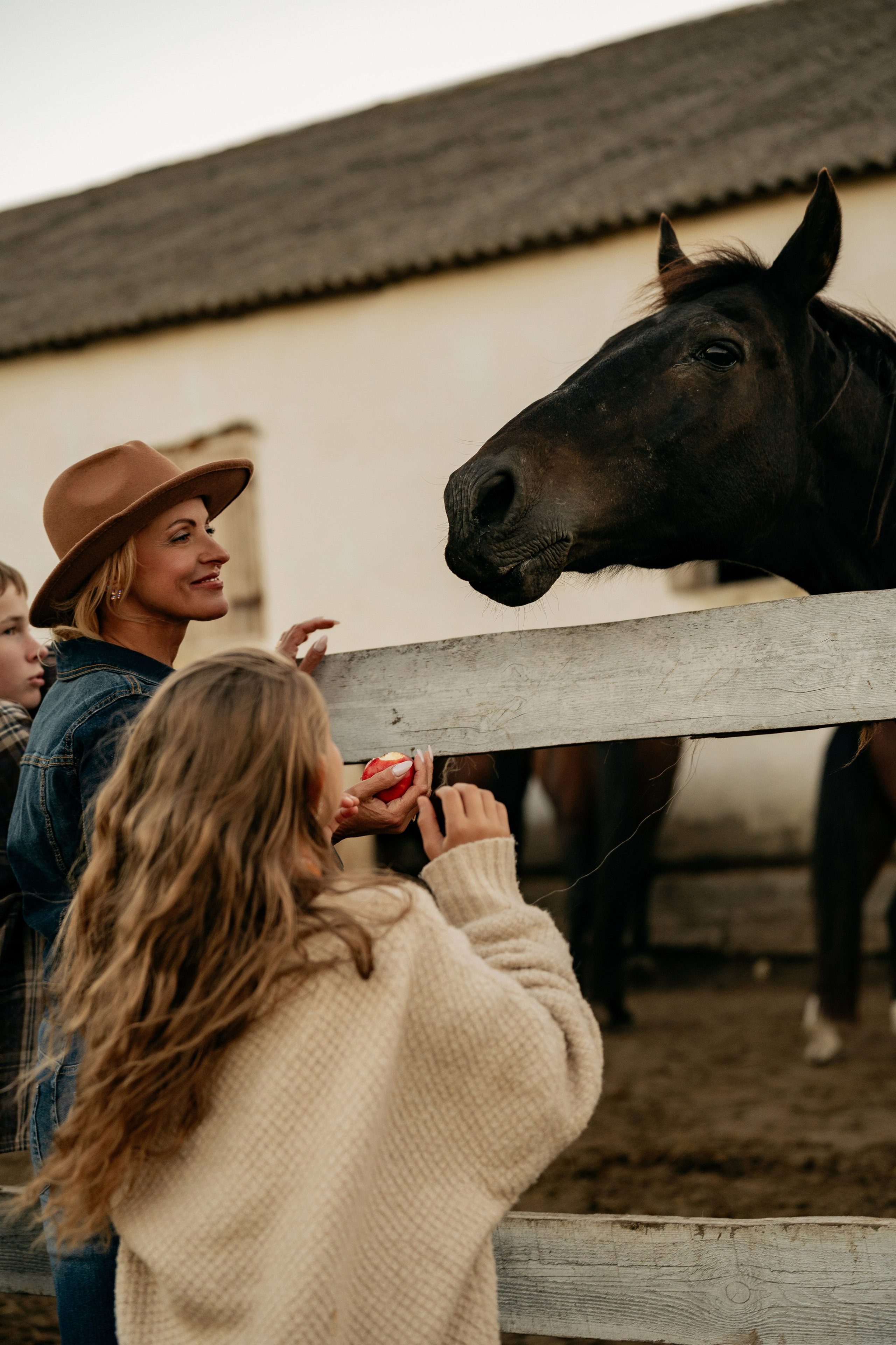 Семейная любовь на фото в Анапе: мама с сыном и дочерью ухаживают за лошадьми на эко-комплексе «Ферма».