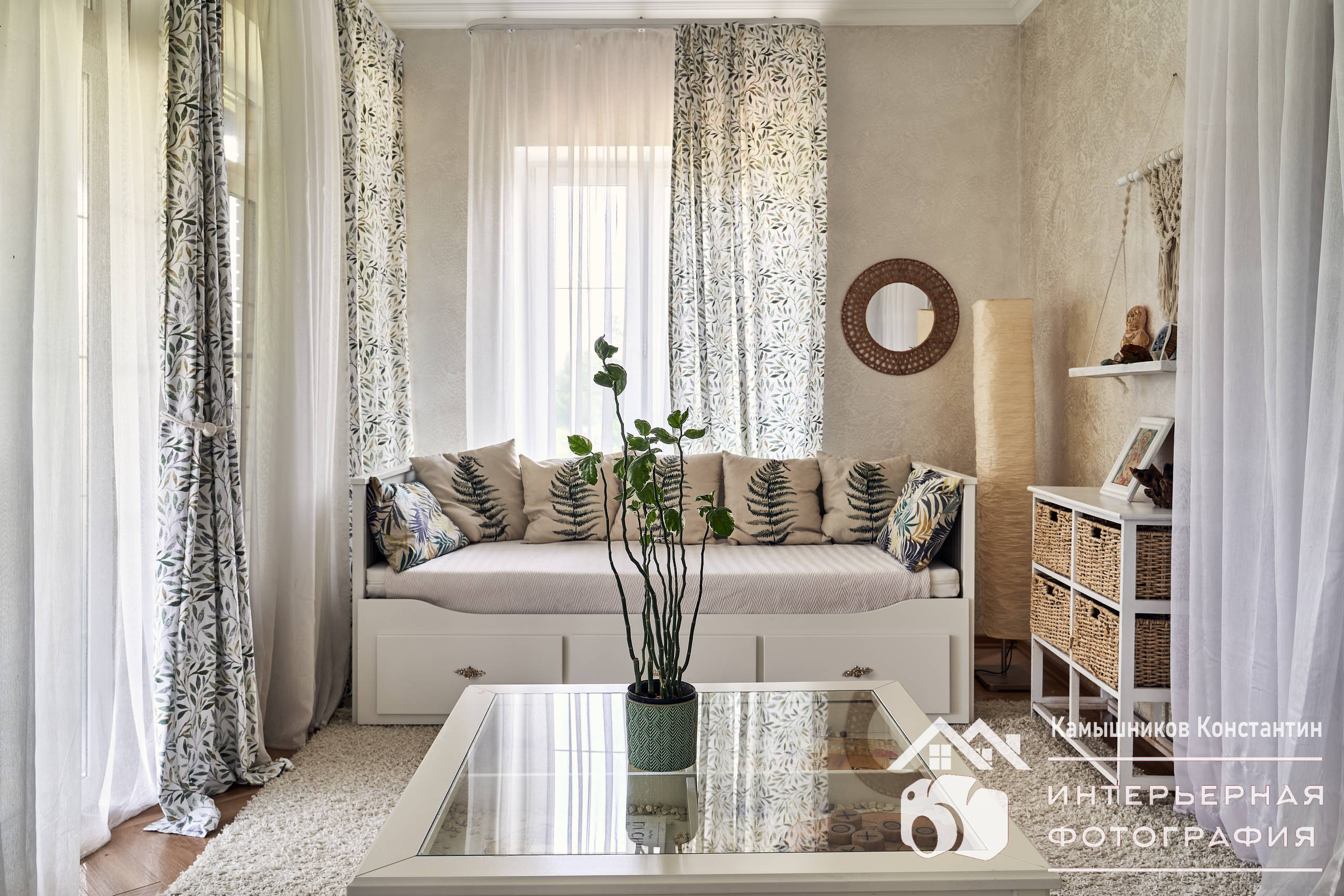 Интерьерная съемка комнаты отдыха с прекрасным диваном, стеклянным журнальным столиком и стильными стеллажами в загородном доме в Подмосковье