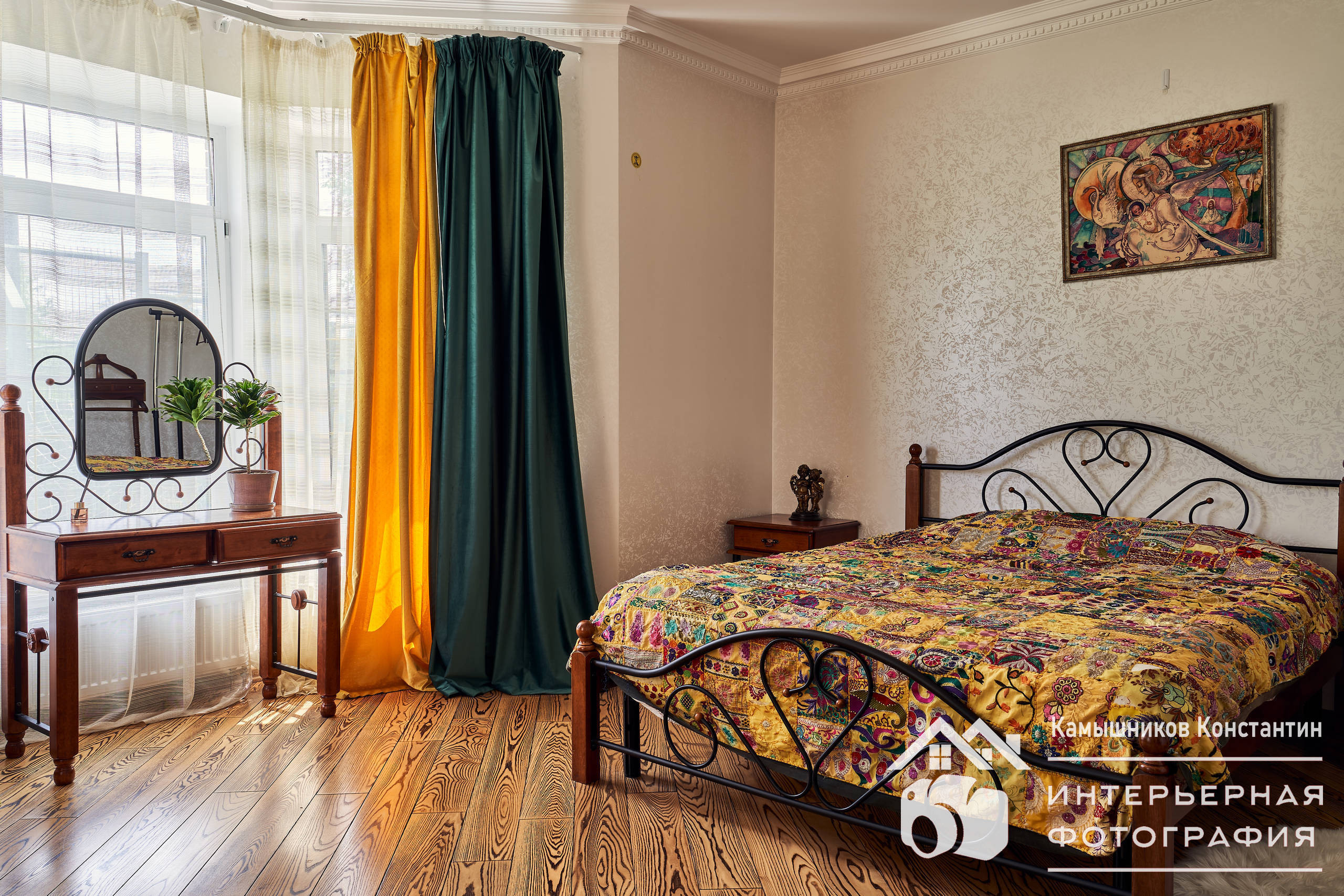 Интерьерная фотография спальни с двуспальной кроватью, столиком, картиной и большим окном