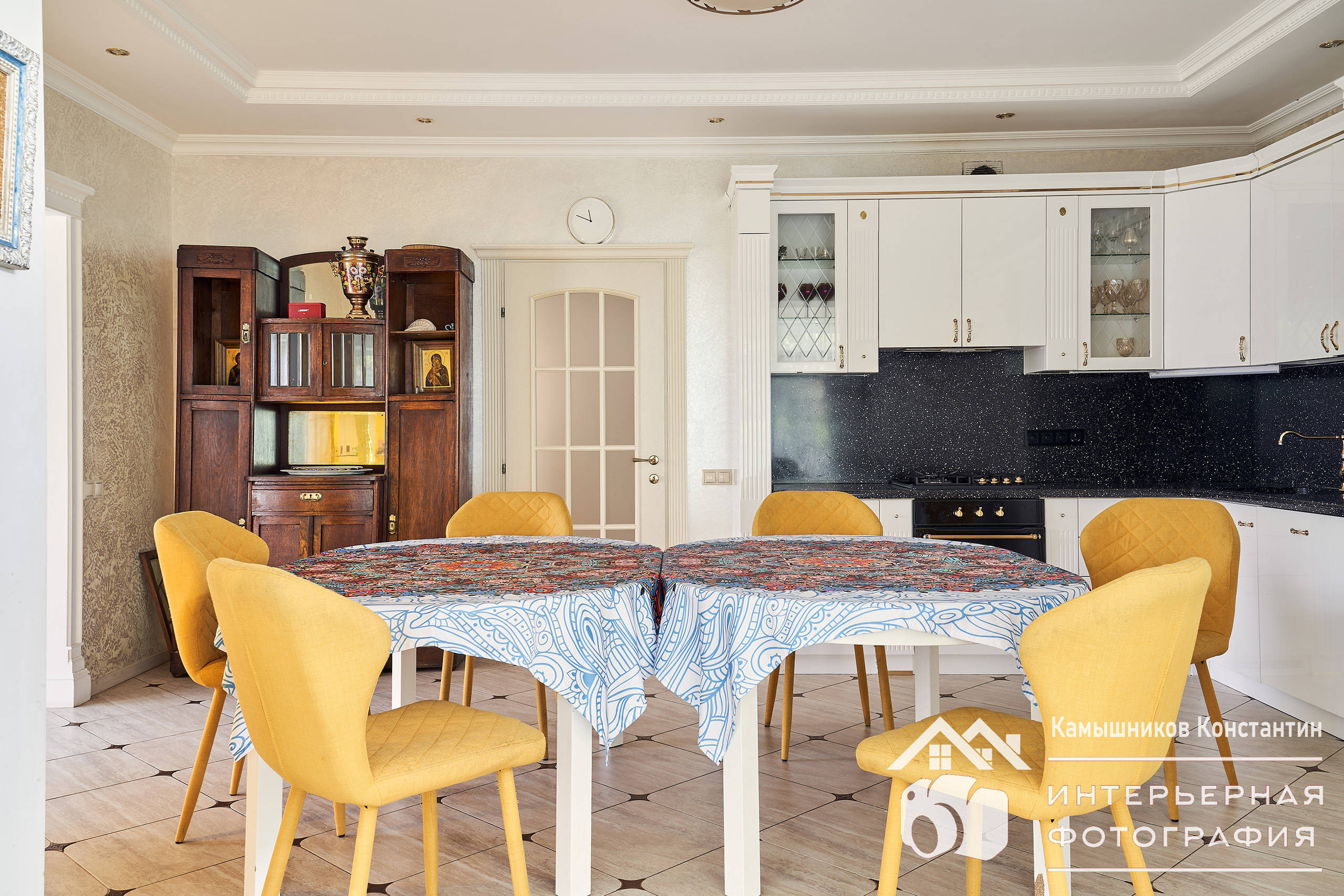 Интерьерная фотография обеденной зоны в загородном доме в Подмосковье: стол, стулья, кухонные шкафы и места приготовления пищи