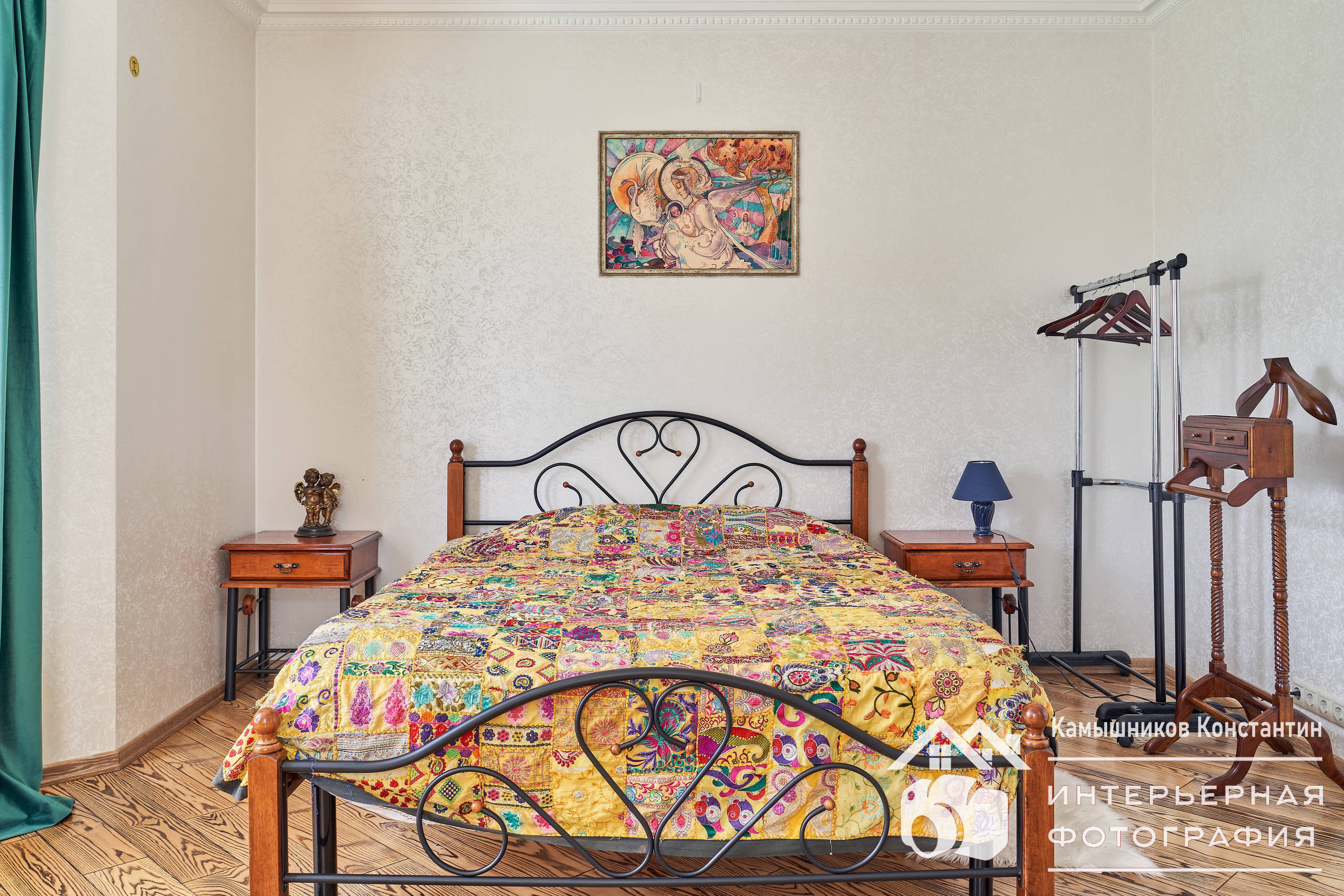 Интерьерная съемка, фронтальный вид на двуспальную кровать, прикроватные столики и картину над кроватью