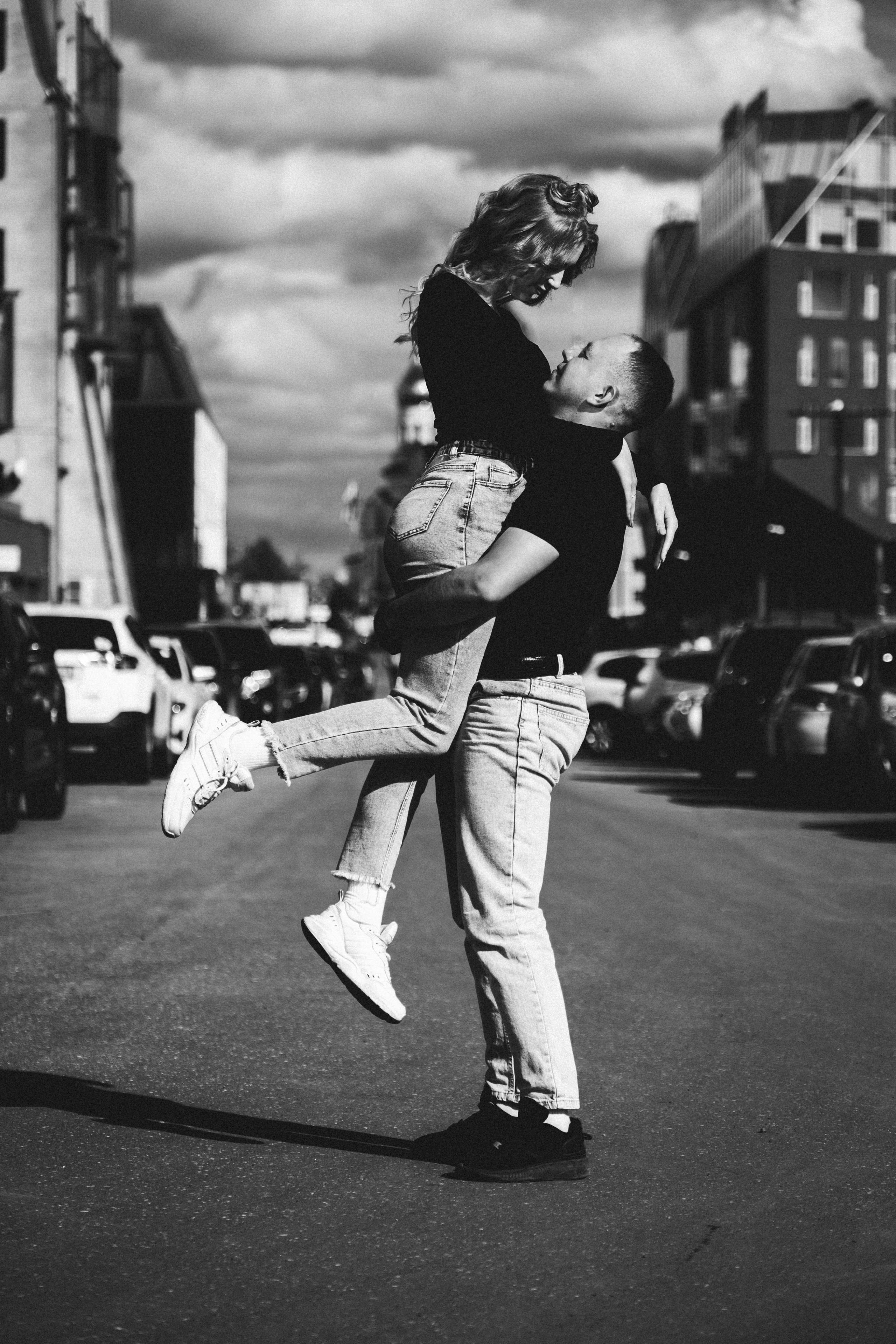 Молодая пара мужчина и девушка обнимаются городских локациях в черных футболках и синих джинсах, лав стори для влюбленной пары на кануне свадьбы