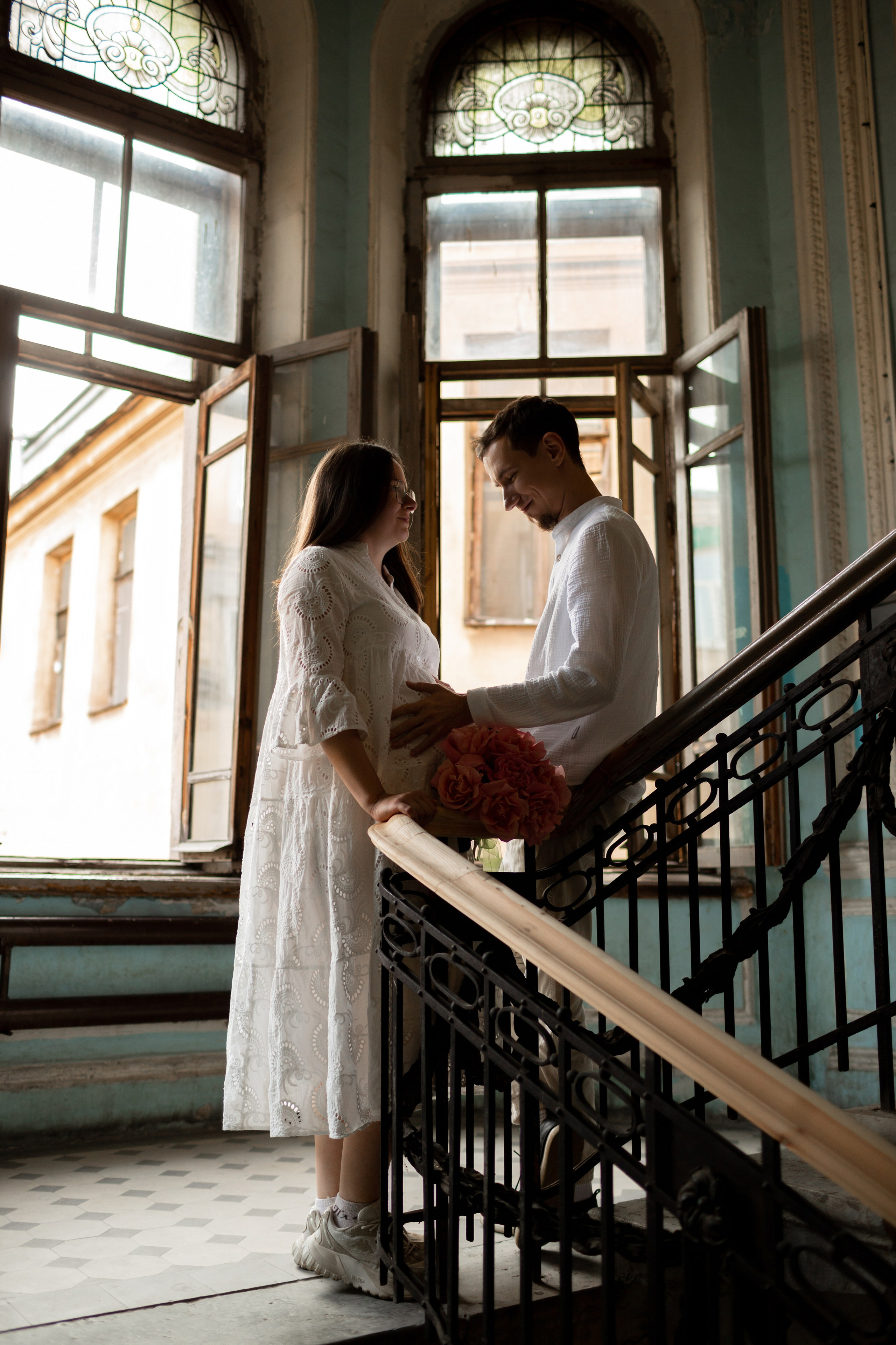 Девушка в кружевном платье у кованых перил парадной.