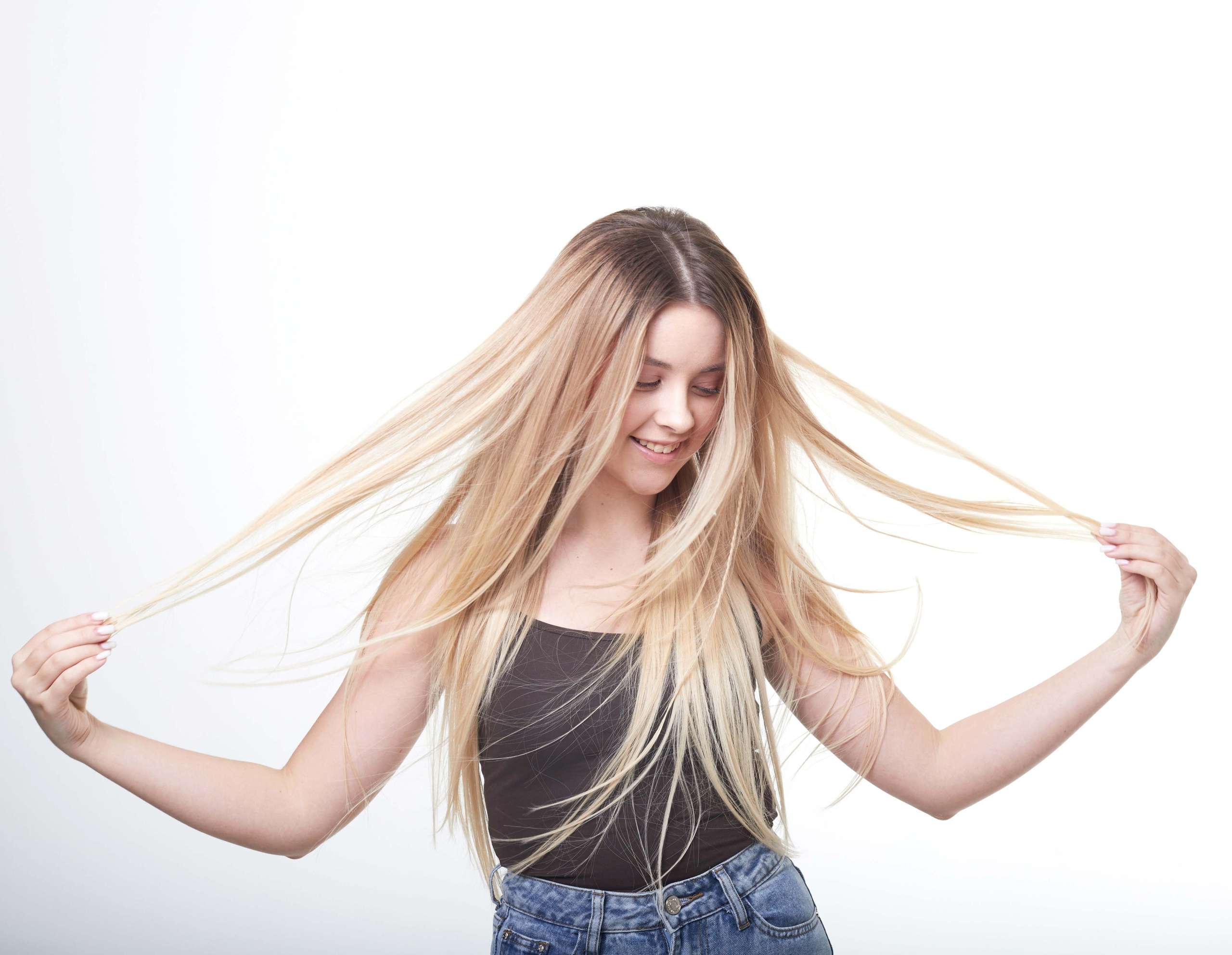 Студийная фотосессия девушки, играющей с длинными волосами.