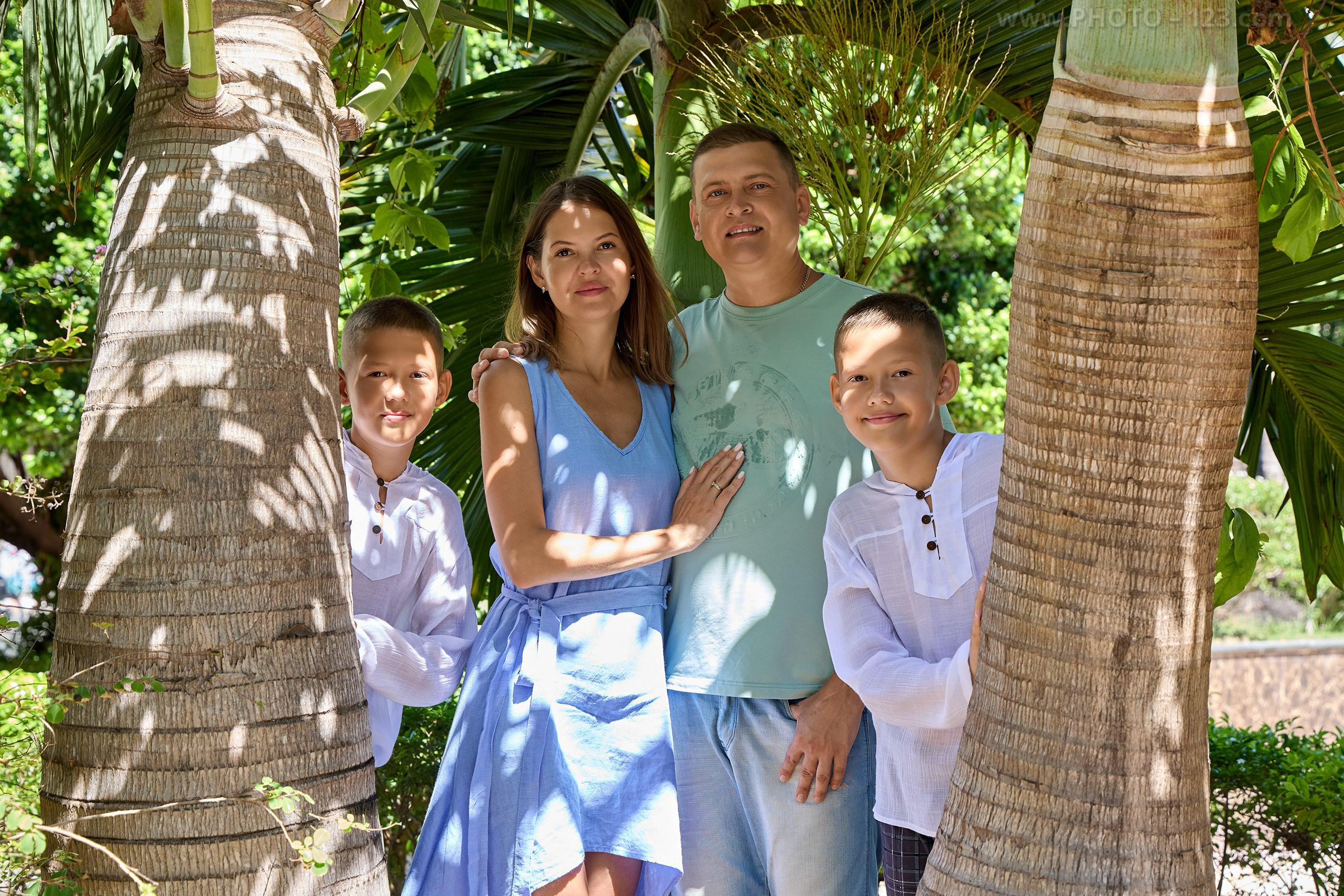 Close-up family portrait framed by tropical palm trees | Professional photography by Dima