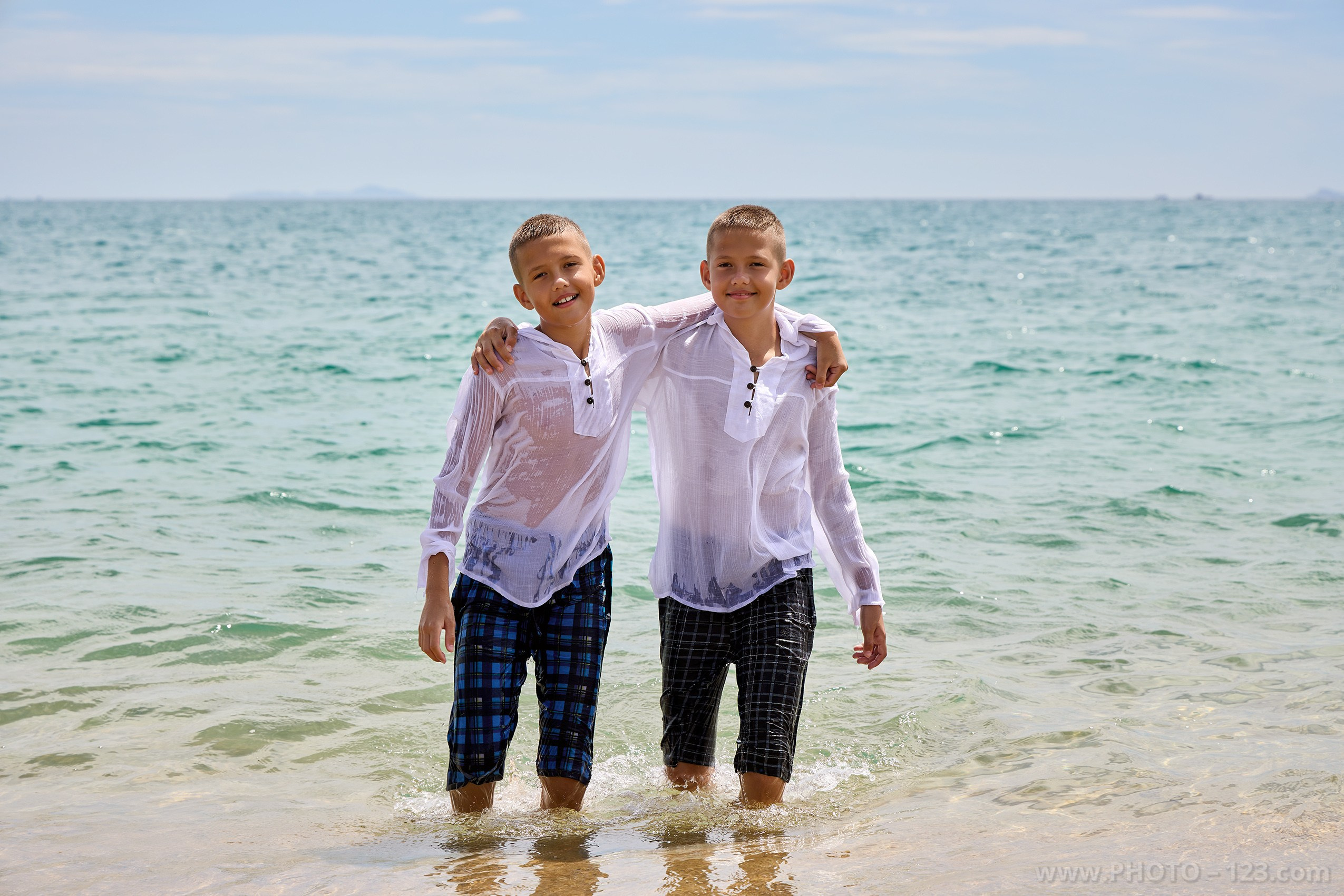 Twin brothers hugging in shallow ocean water during photoshoot | Captured by expert with 20+ years experience