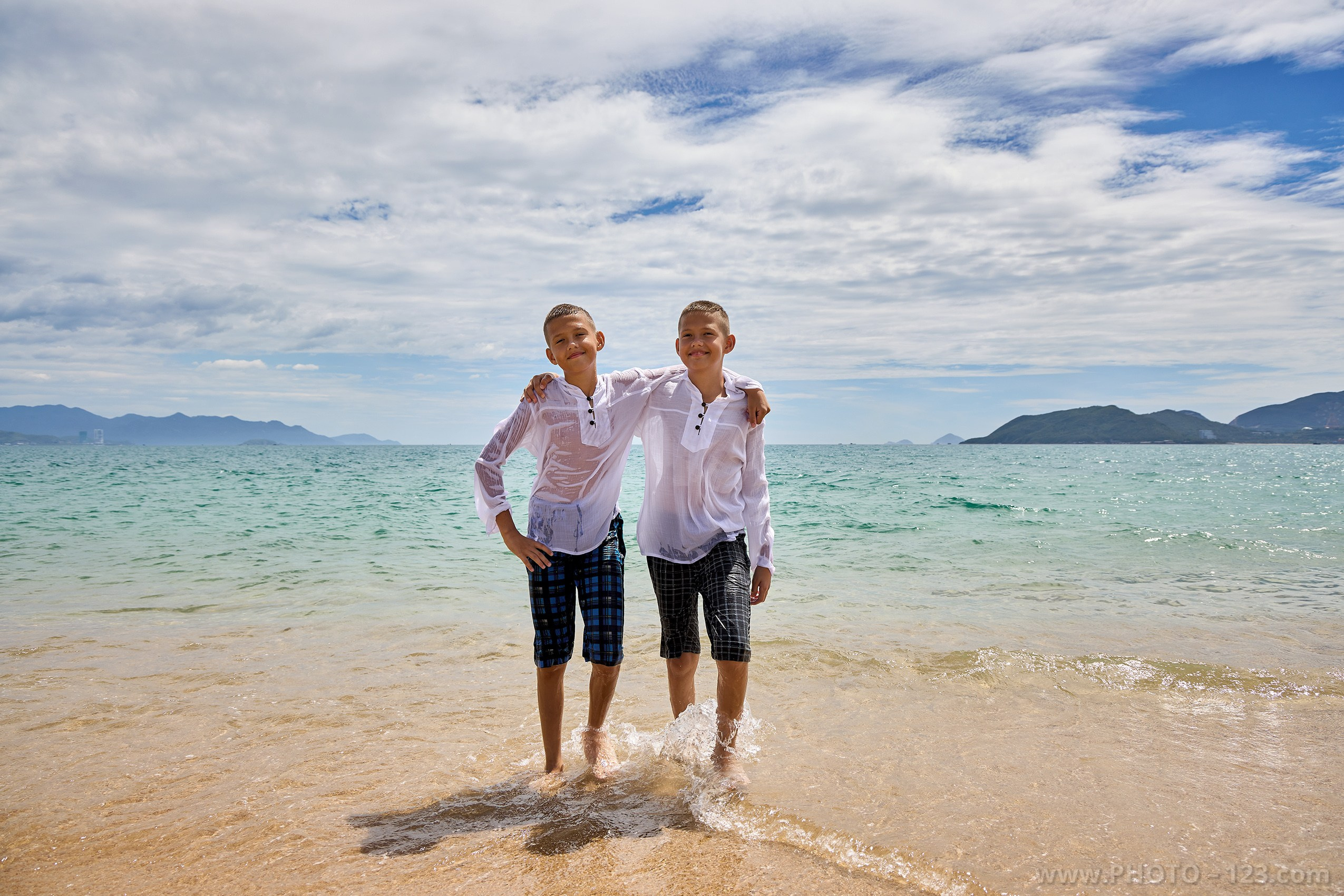 Twin brothers standing in shallow seawater on sunny beach | Nha Trang photographer Dima