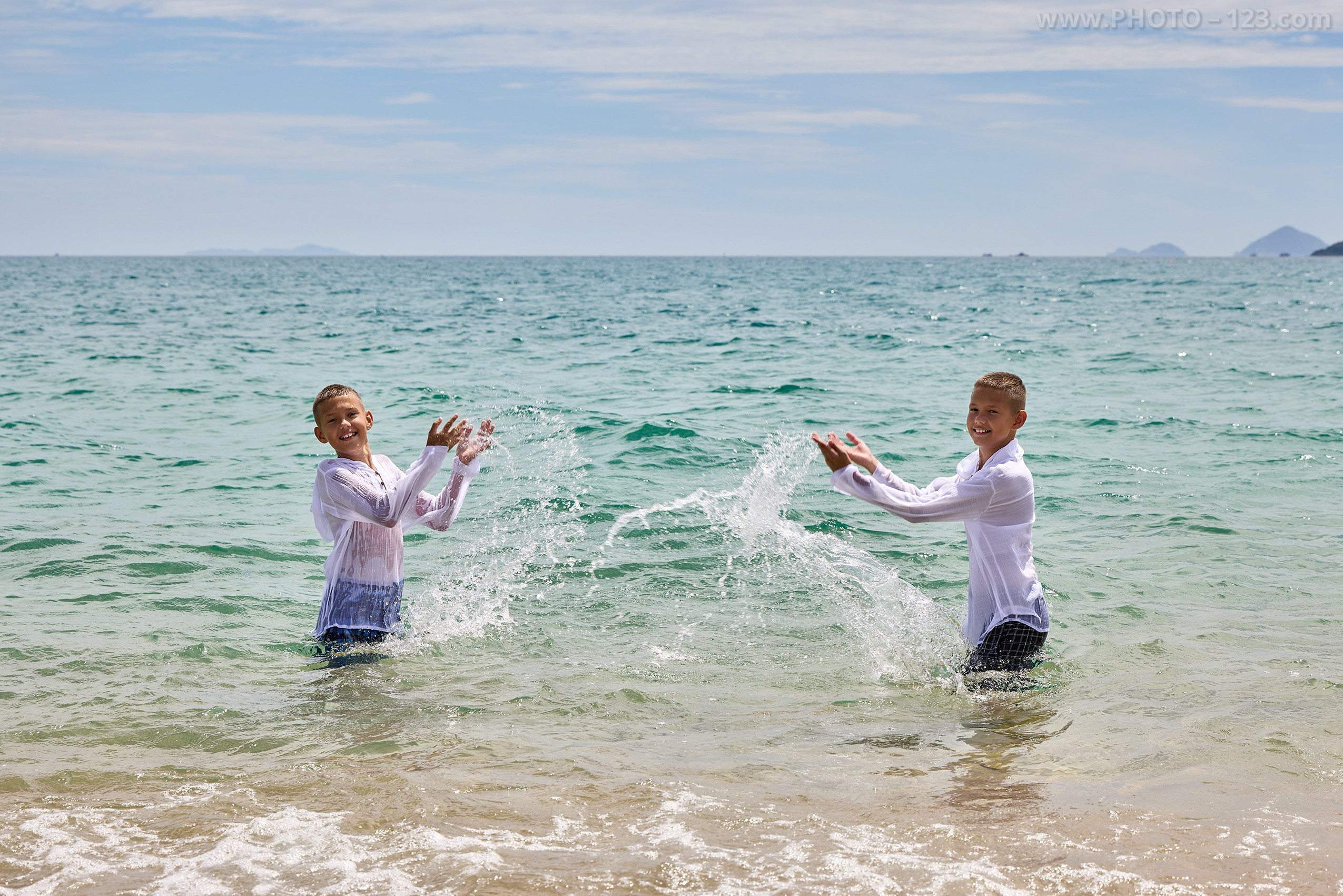 Twin boys playing and splashing seawater at each other | Professional photography by Dima