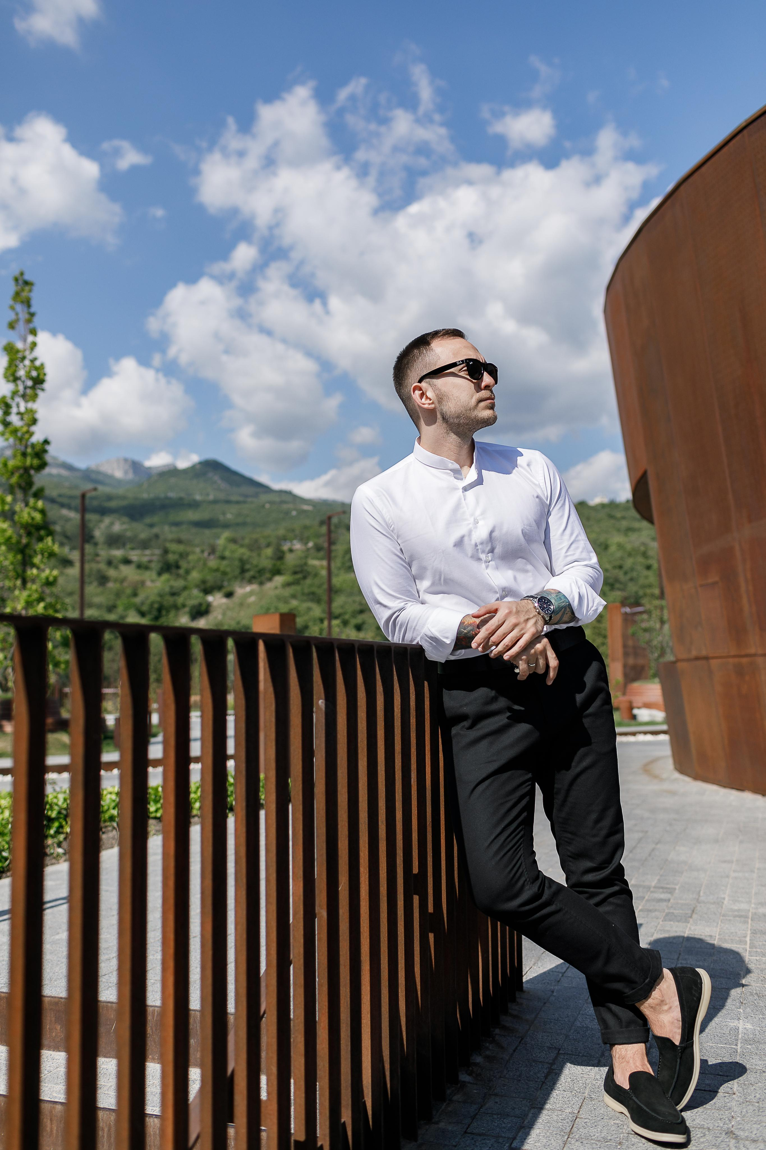 Жених в стильном костюме позирует для профессионального фотографа.