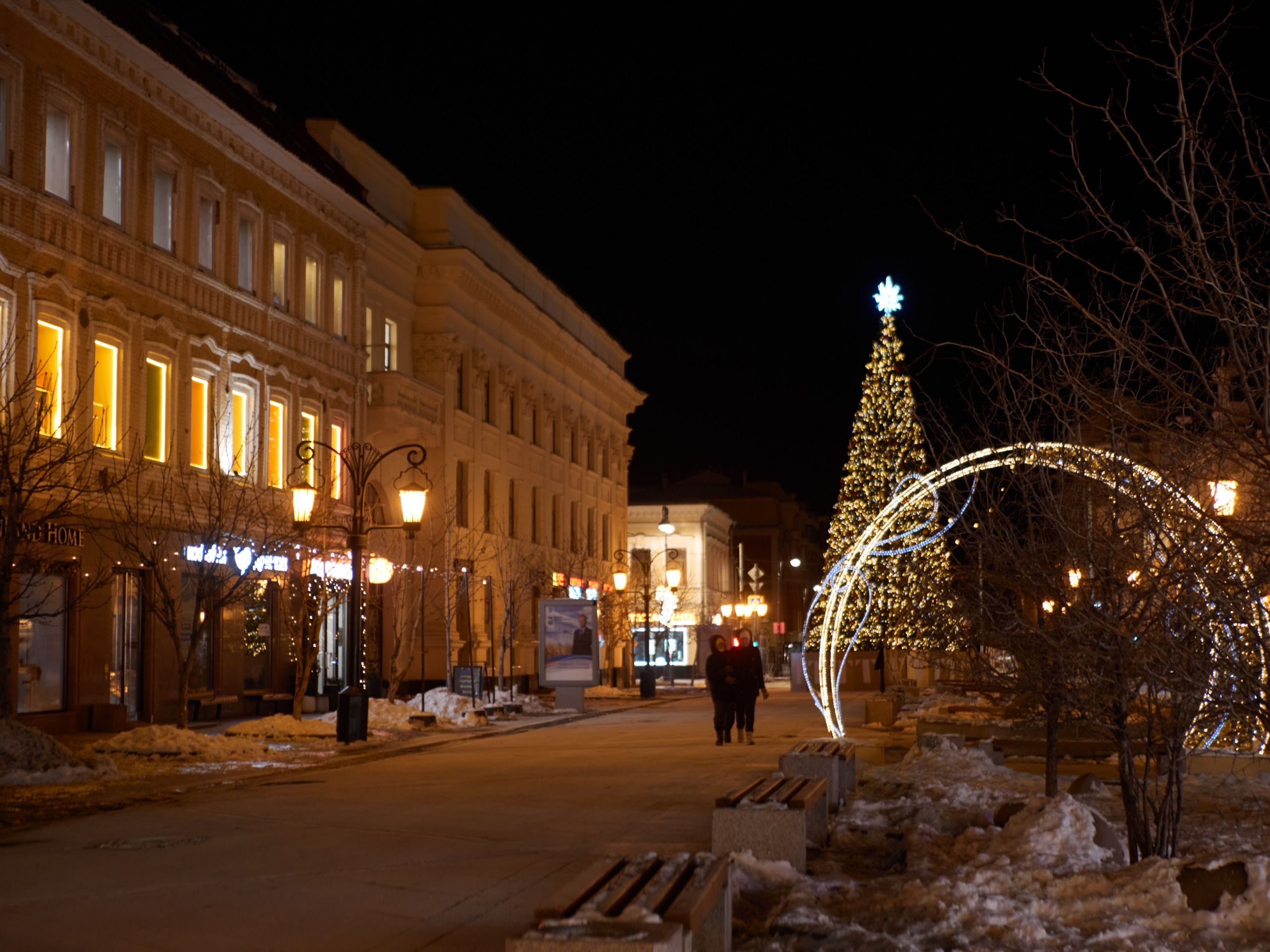 Вид на украшенные витрины магазинов и яркие гирлянды на улице Ленинградской.