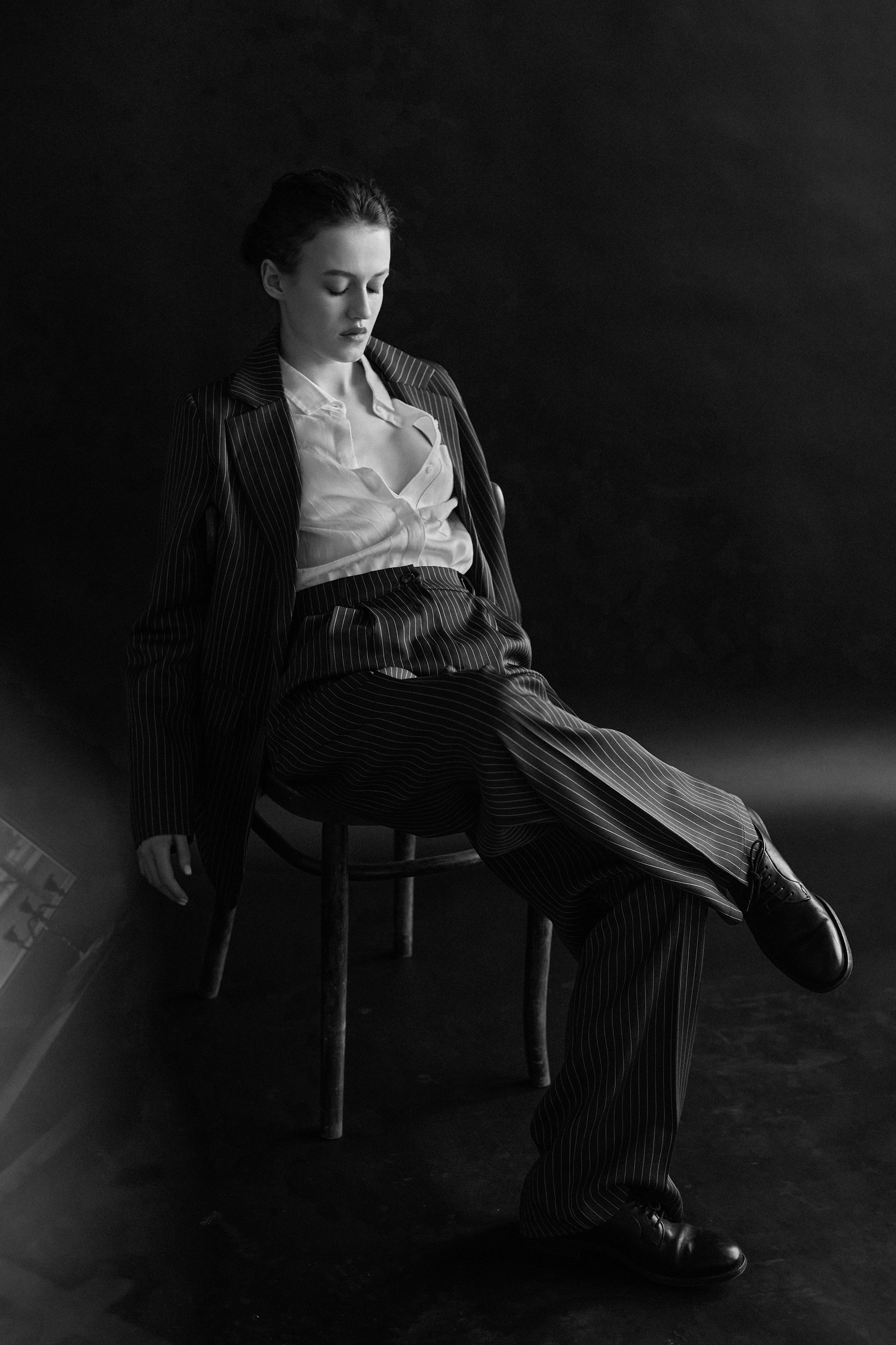 Фотограф в Москве. Студия. Студийный портрет. Девушка в пиджаке. Девушка на стуле на черном фоне. Красивая девушка в мужском костюме. Женский портрет. Черно-белое фото.