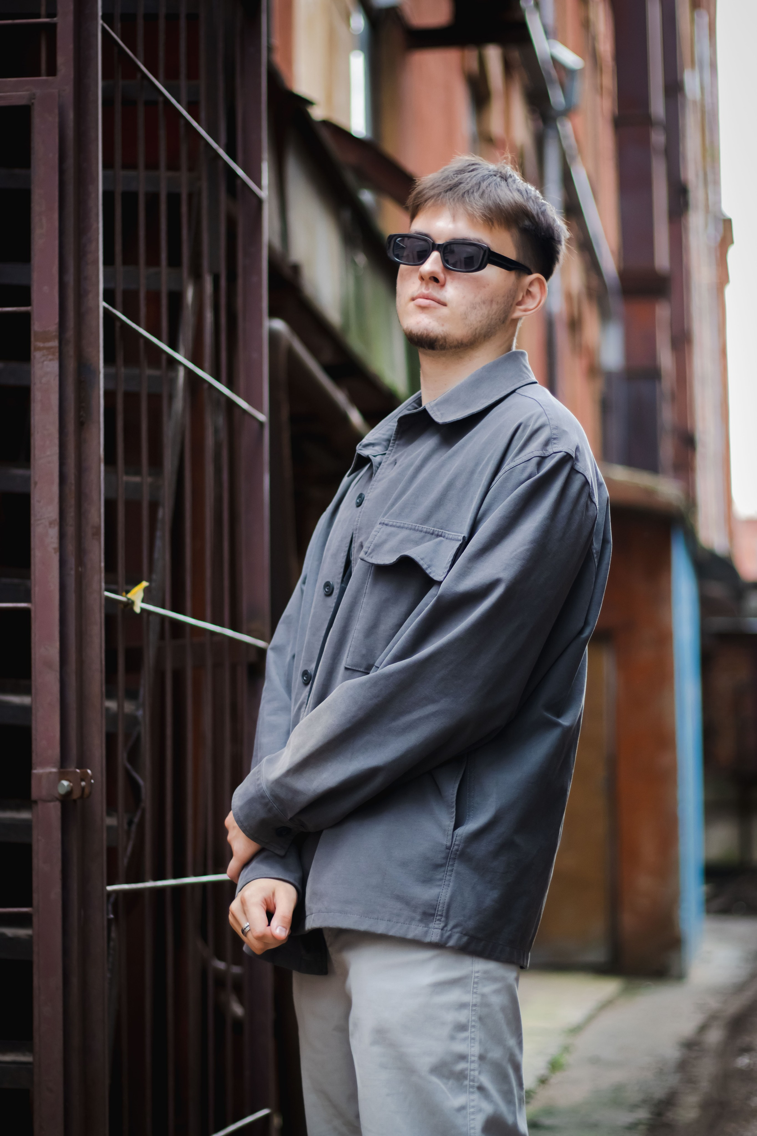 стоит парень в округ металлические прутья и старые здания