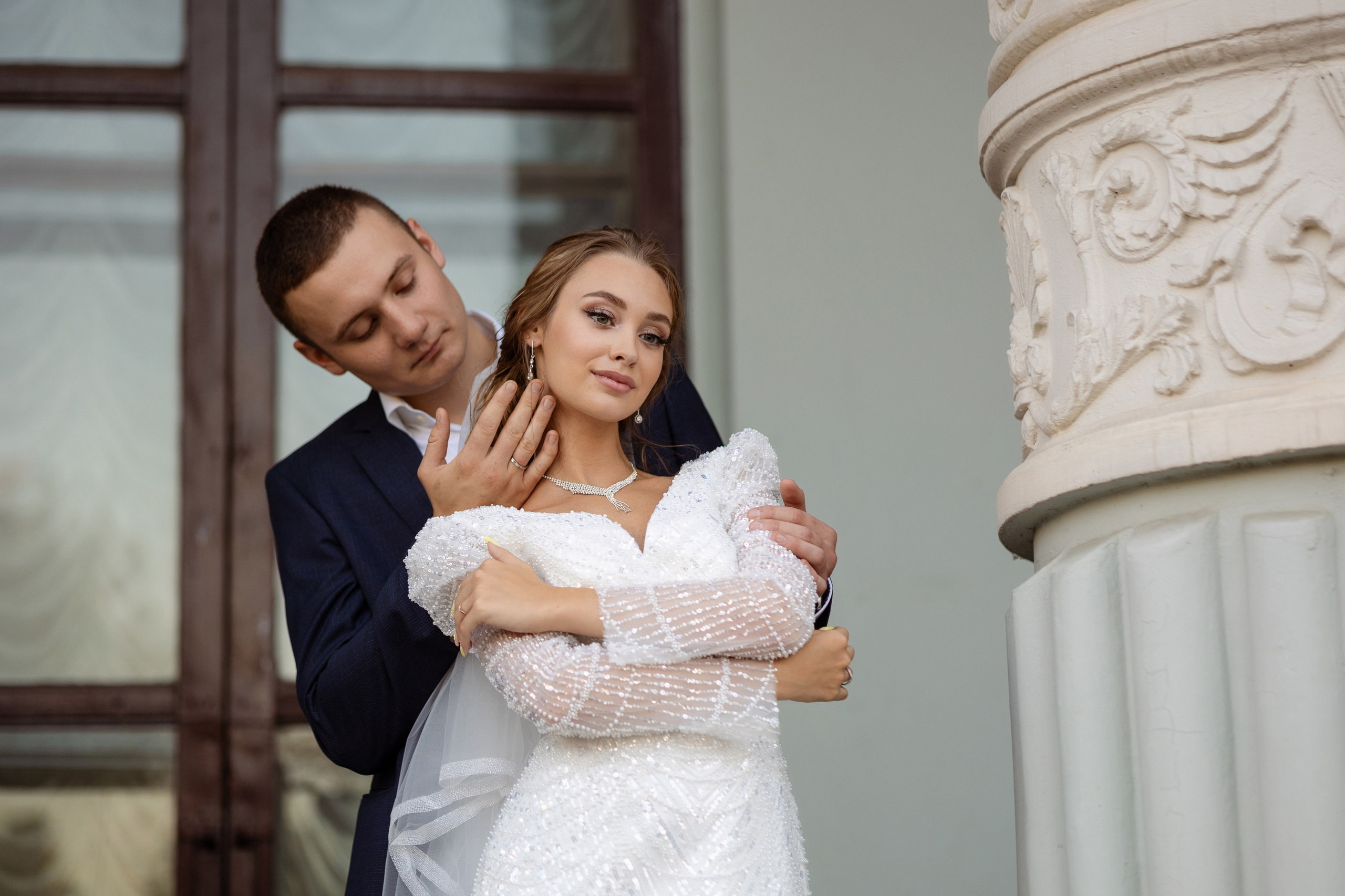Невеста у колонны в объятьях жениха.