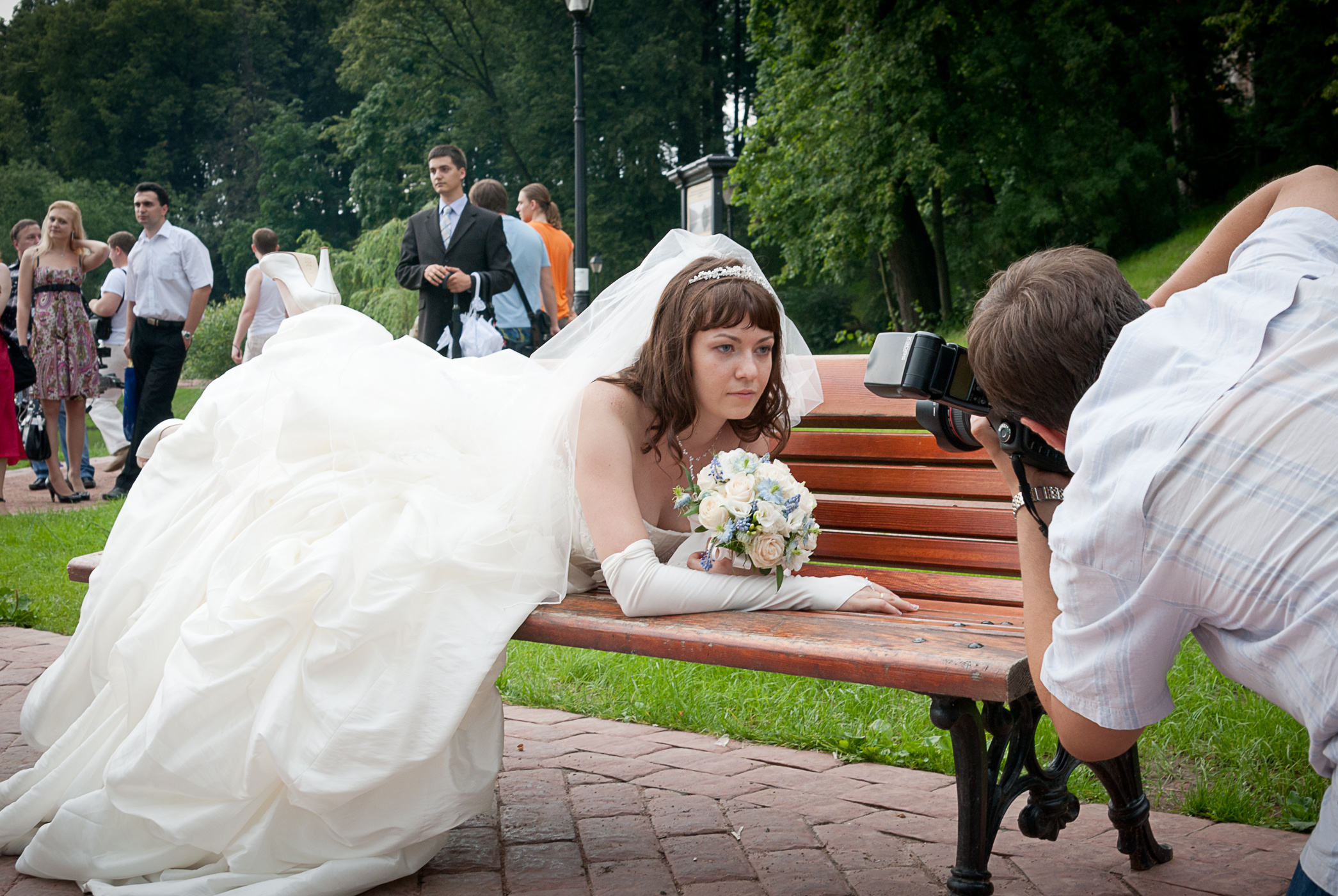 Невеста лежит на скамье и позирует фотографу бэкстейдж