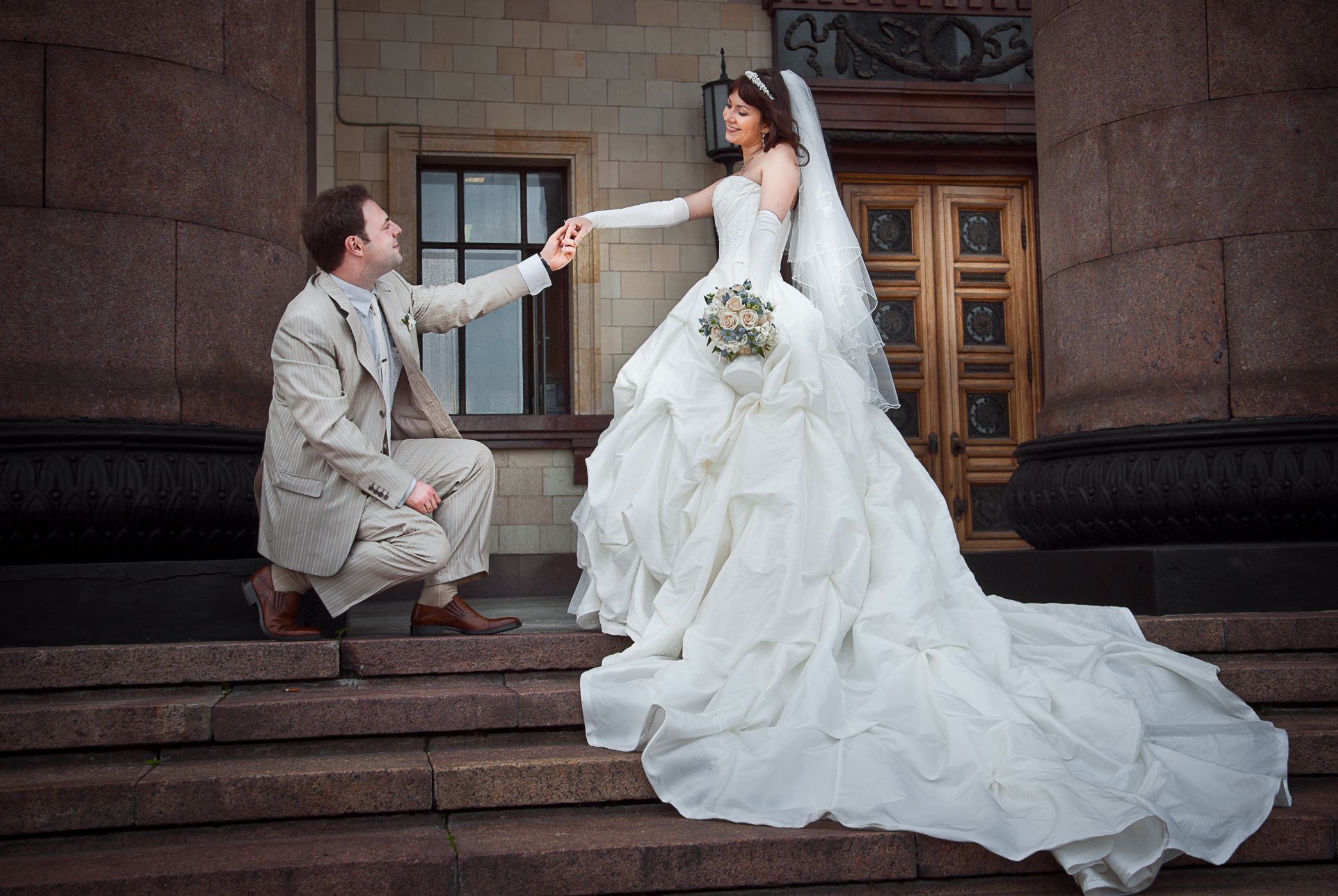 Жених перед невестой на колене, красивое свадебное платье