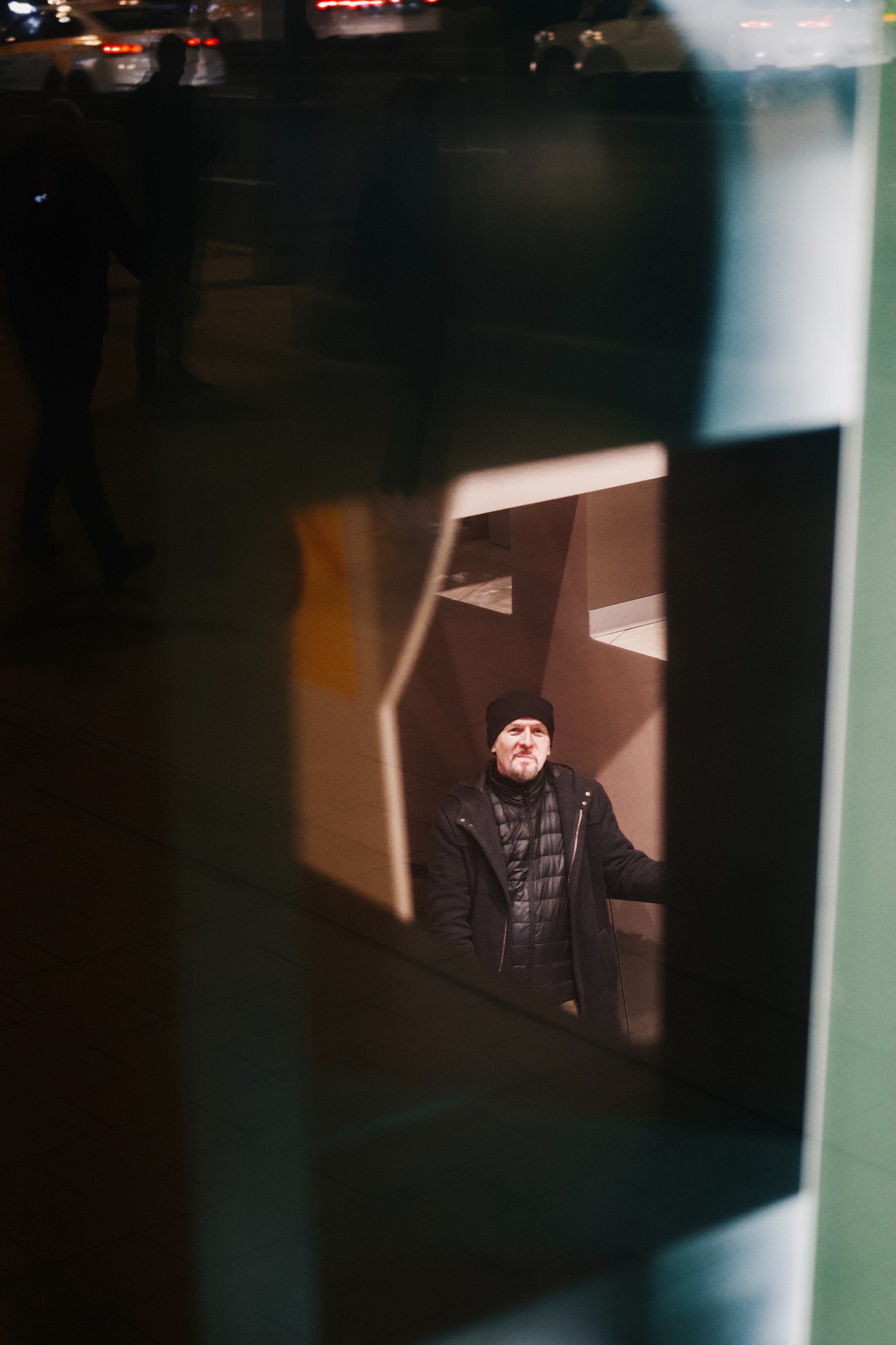 Отражение мужчины на эскалаторе в витрине магазина