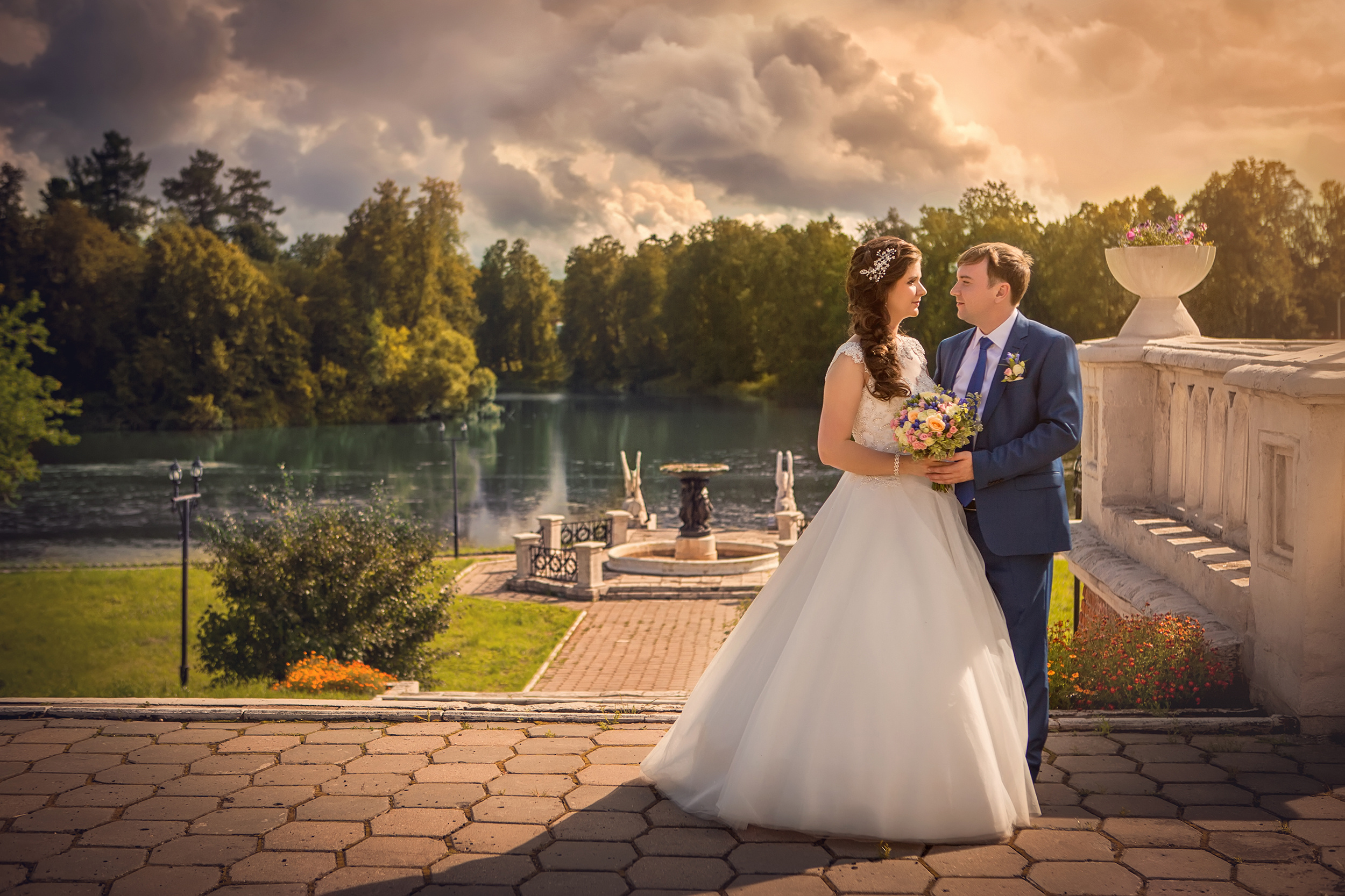 Фотограф фотографирует жениха и невесту на фоне красивого заката