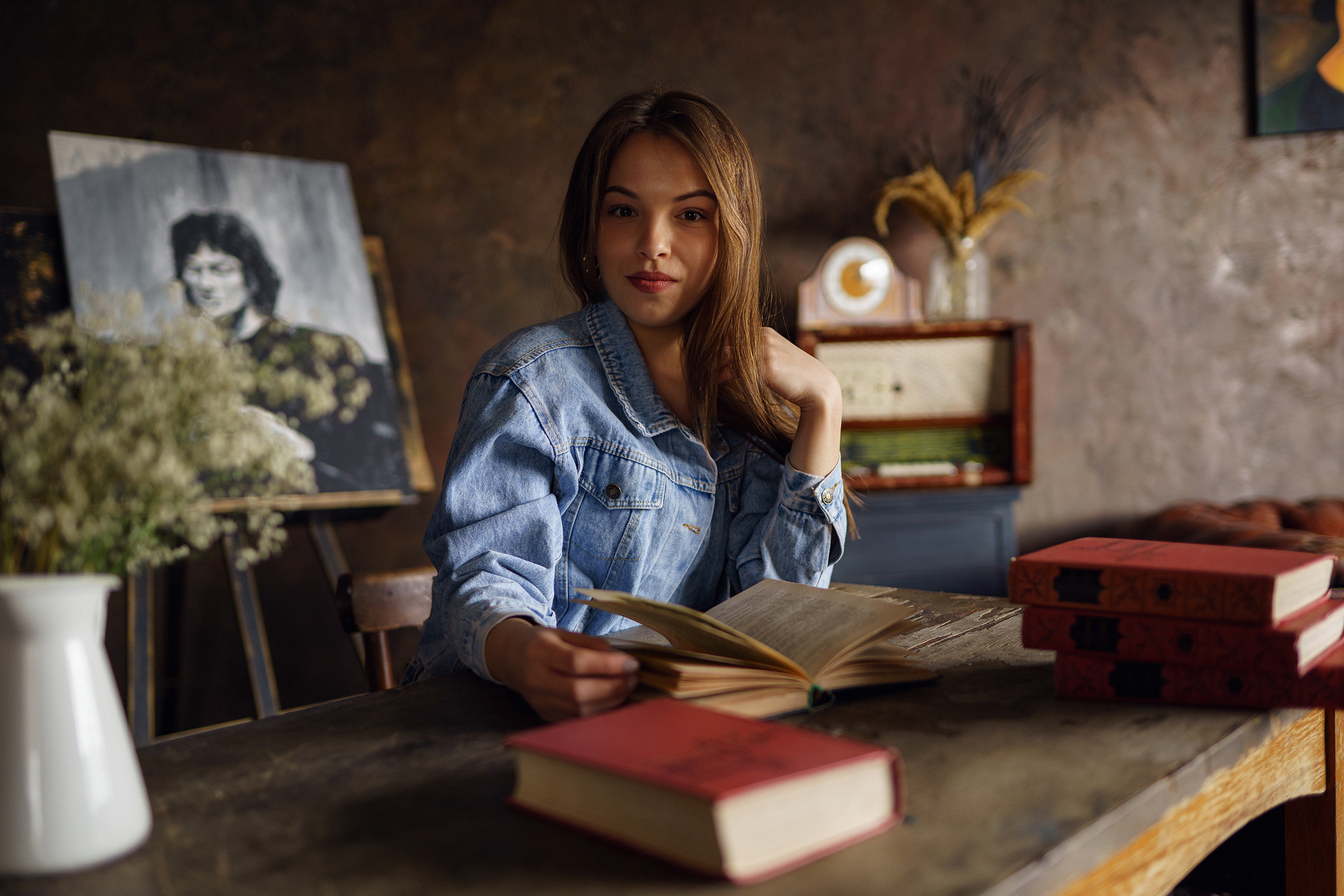 Женский портрет девушка сидит за письменным  столом с книжкой в руке