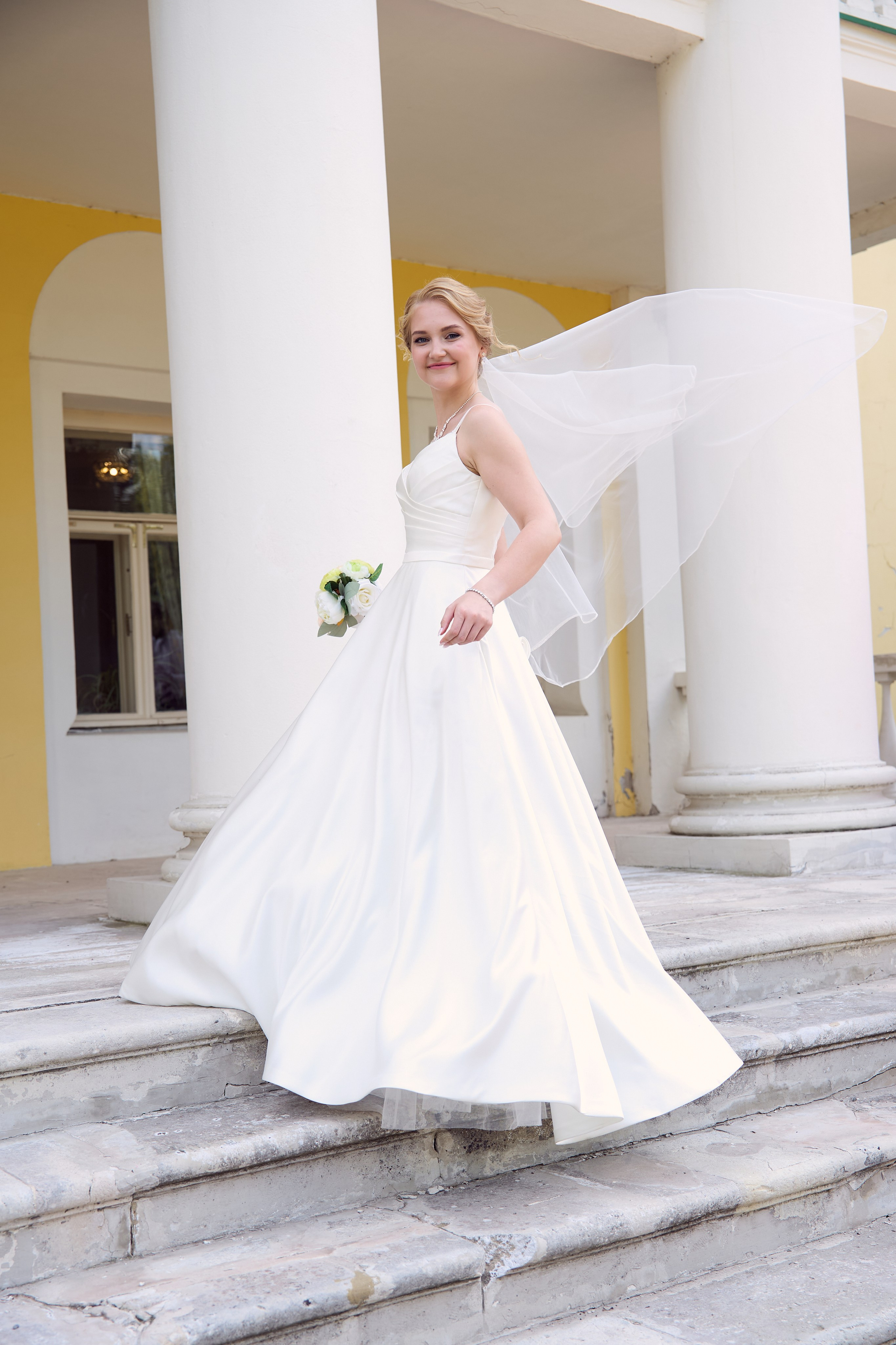 невеста с развевающейся фатой на ступенях