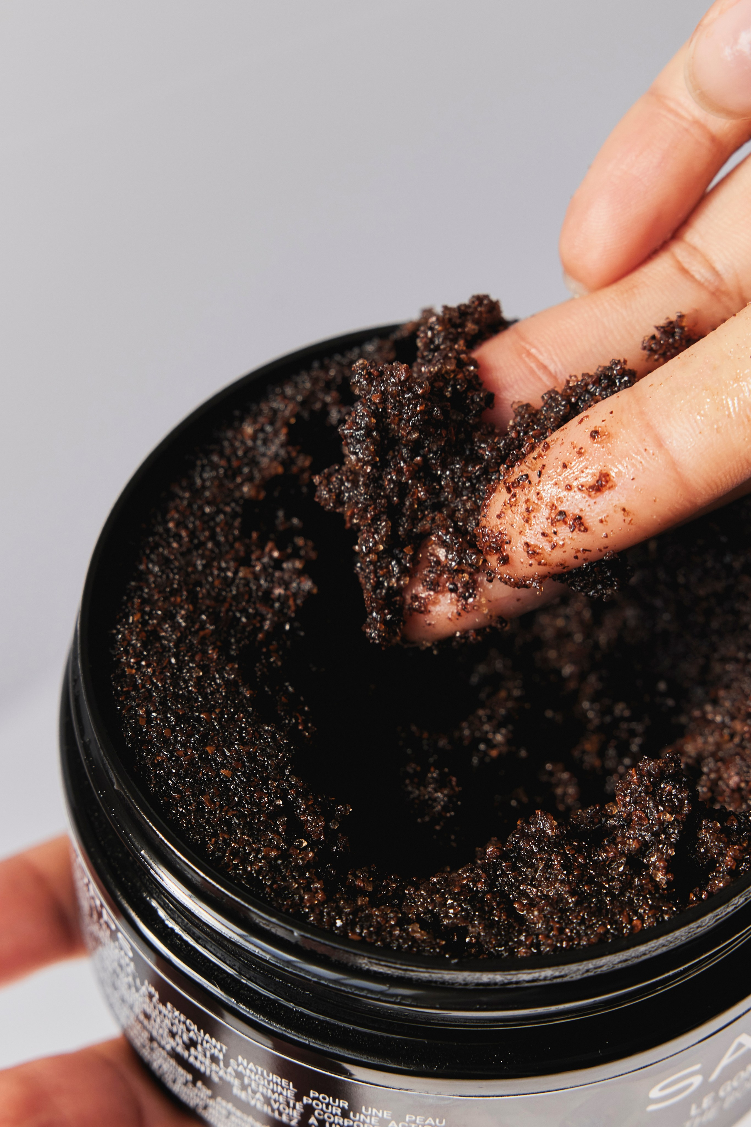 Close-up of rich, exfoliating coffee scrub in a jar, perfect for a natural skincare campaign.